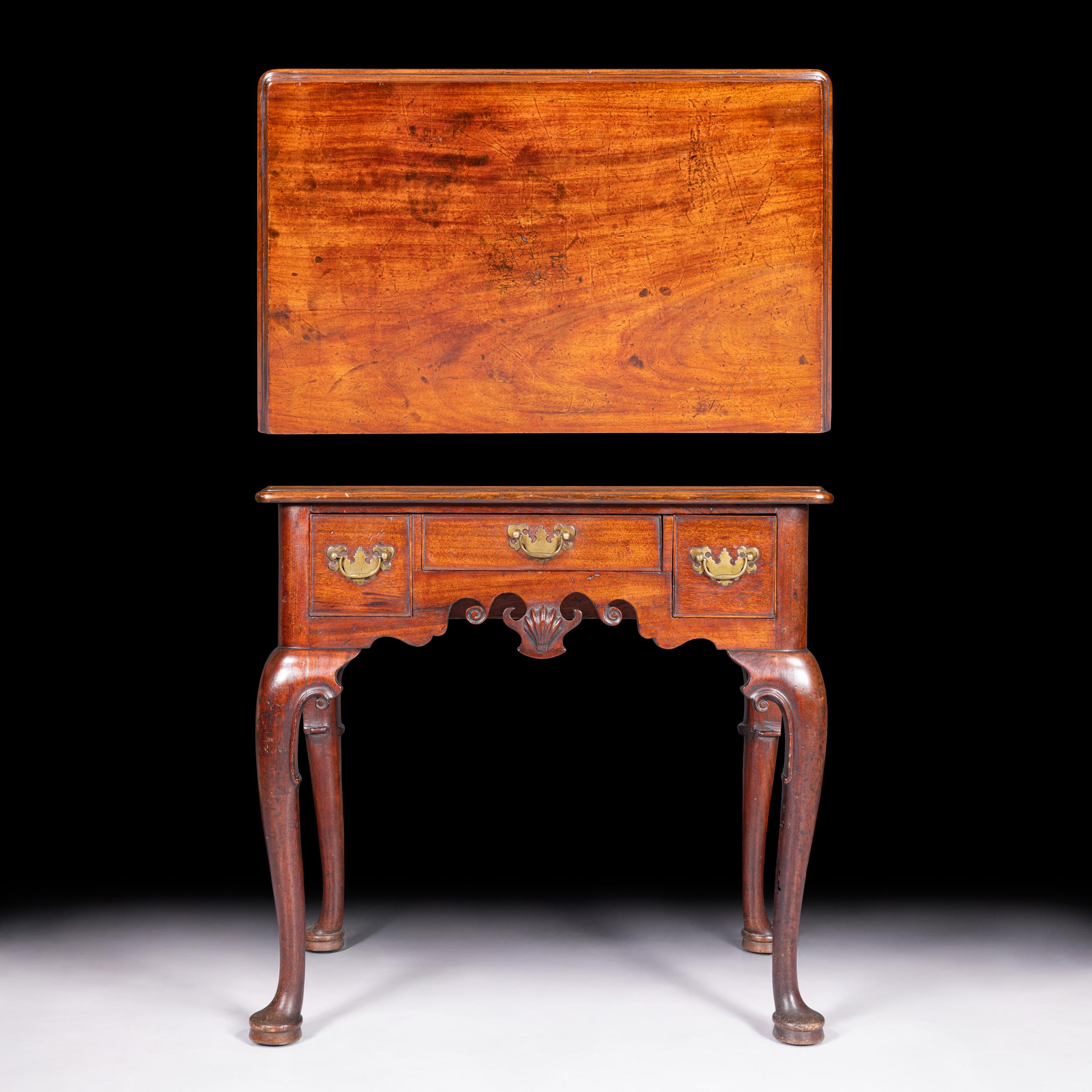 A fine and elegant George II period mahogany lowboy, displaying excellent color and patination, with refined proportions and crisp carving throughout. The top is of rectangular form with a molded edge above three drawers, arranged with one long