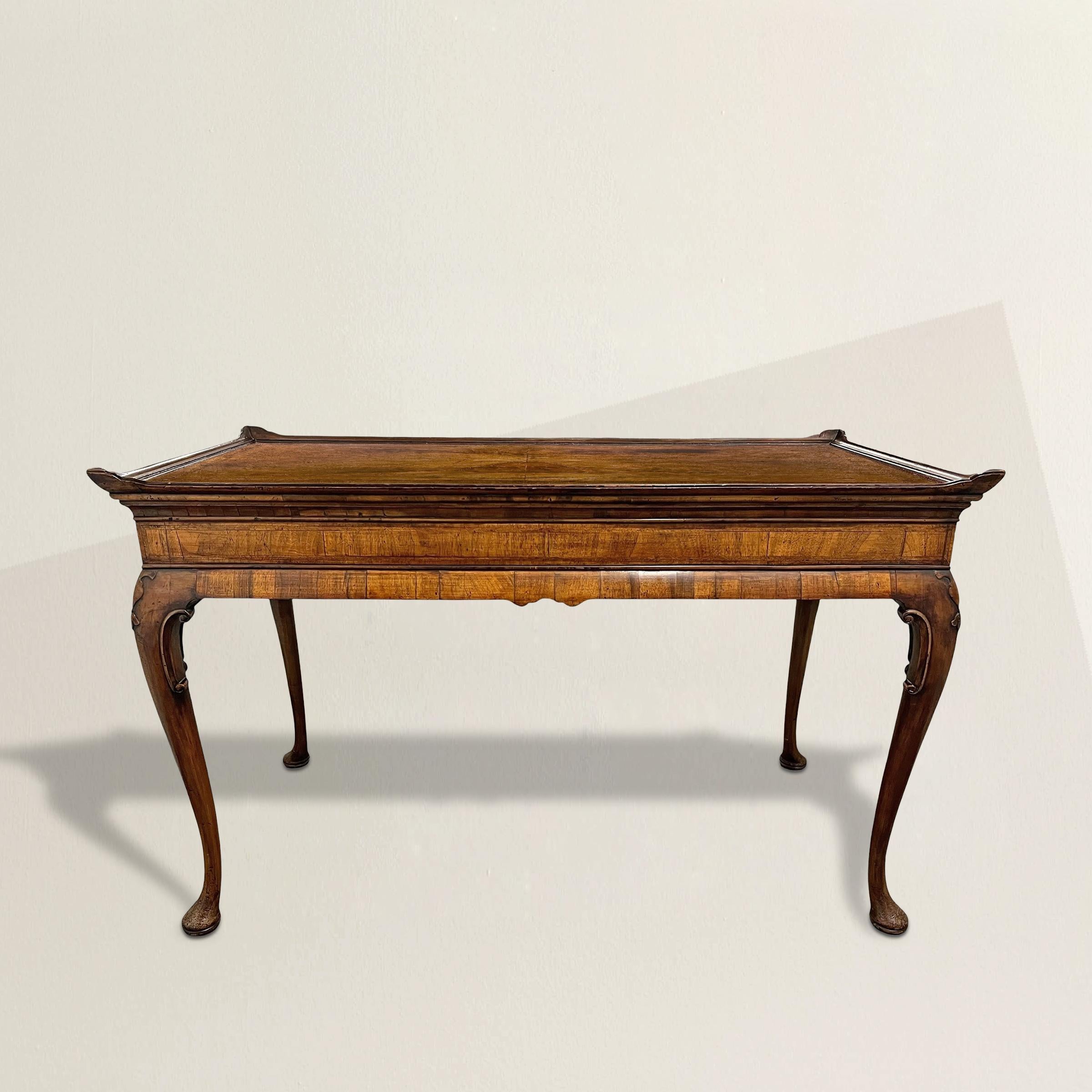 Esta mesa de plata inglesa de nogal de Jorge II ejemplifica el tranquilo refinamiento del diseño de mediados del siglo XVIII. Fabricada hacia 1740, la mesa presenta un tablero de nogal con incrustaciones de sutil parquetería y acabado con un bello y