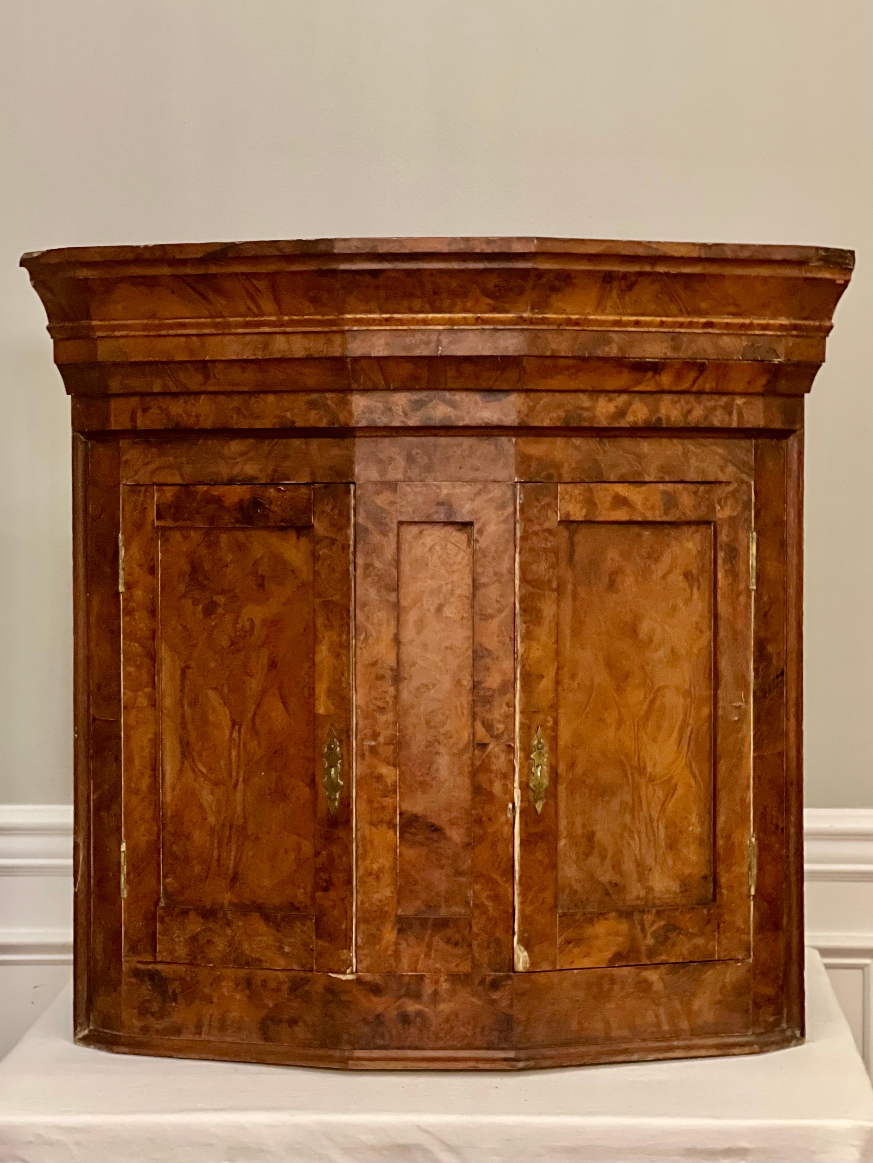 Wonderful 18th century elmwood burl two door hanging corner cupboard.

It features a unique angular shape with a moulded cornice above large paneled doors and center column.  The doors have original tulip bud shaped hardware with key.  The back