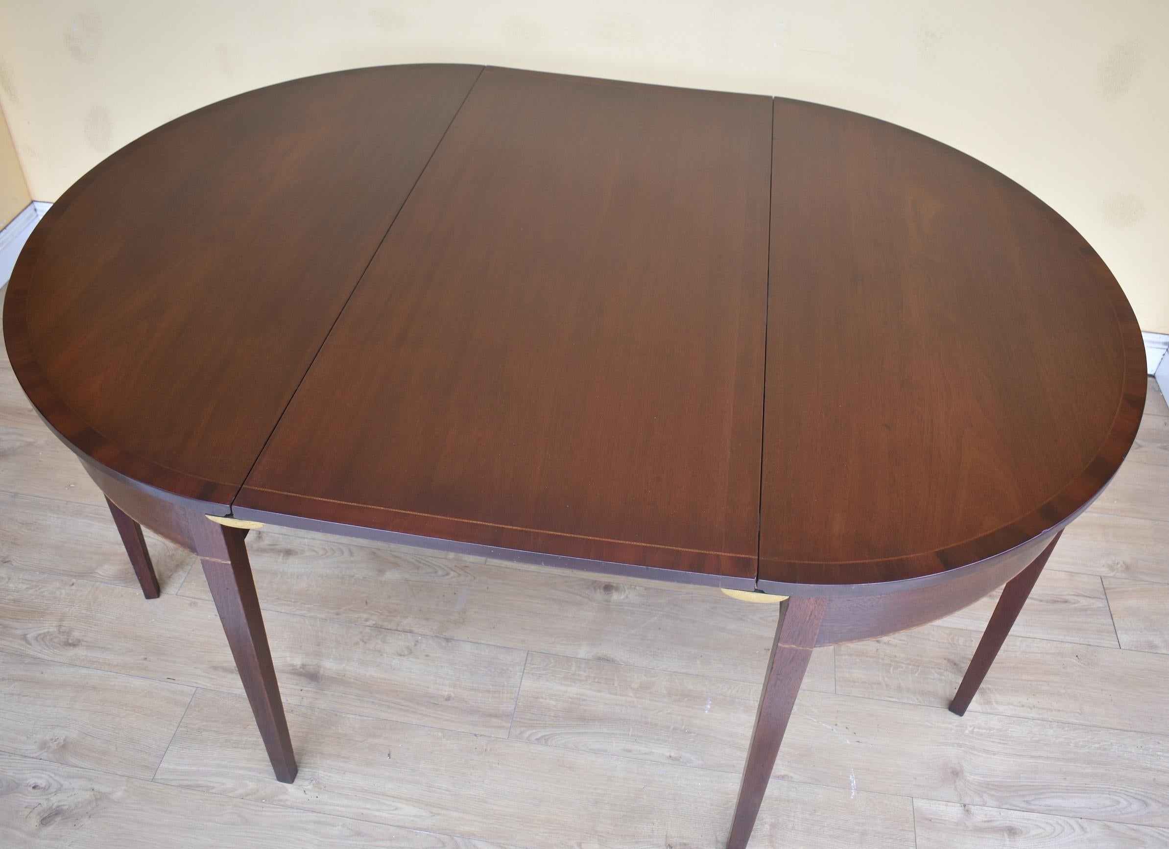 For sale is a good quality George III mahogany D end dining table, having a single additional leaf, the tabletop is oval in form and is inlaid. The two d ends also have further inlay, and stand on square tapered legs. When the table is not in use,