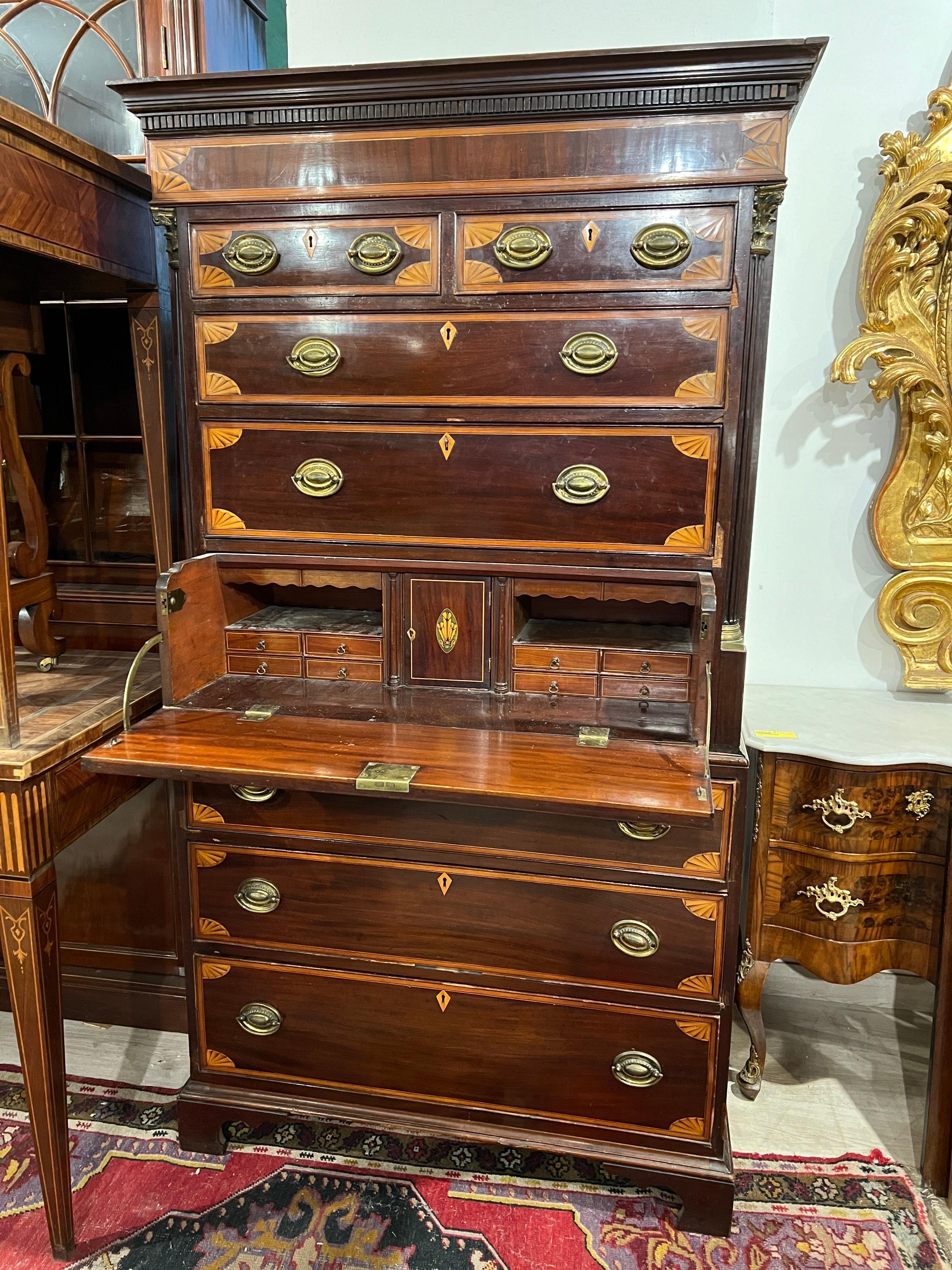 English secretaire with mahogany chest of drawers and finely inlaid in fruitwood and satinwood in the manner of Thomas Sheraton, on the sides also two columns with gilt bronze capitals. 
In the center of the cabinet is the secretaire drawer with a