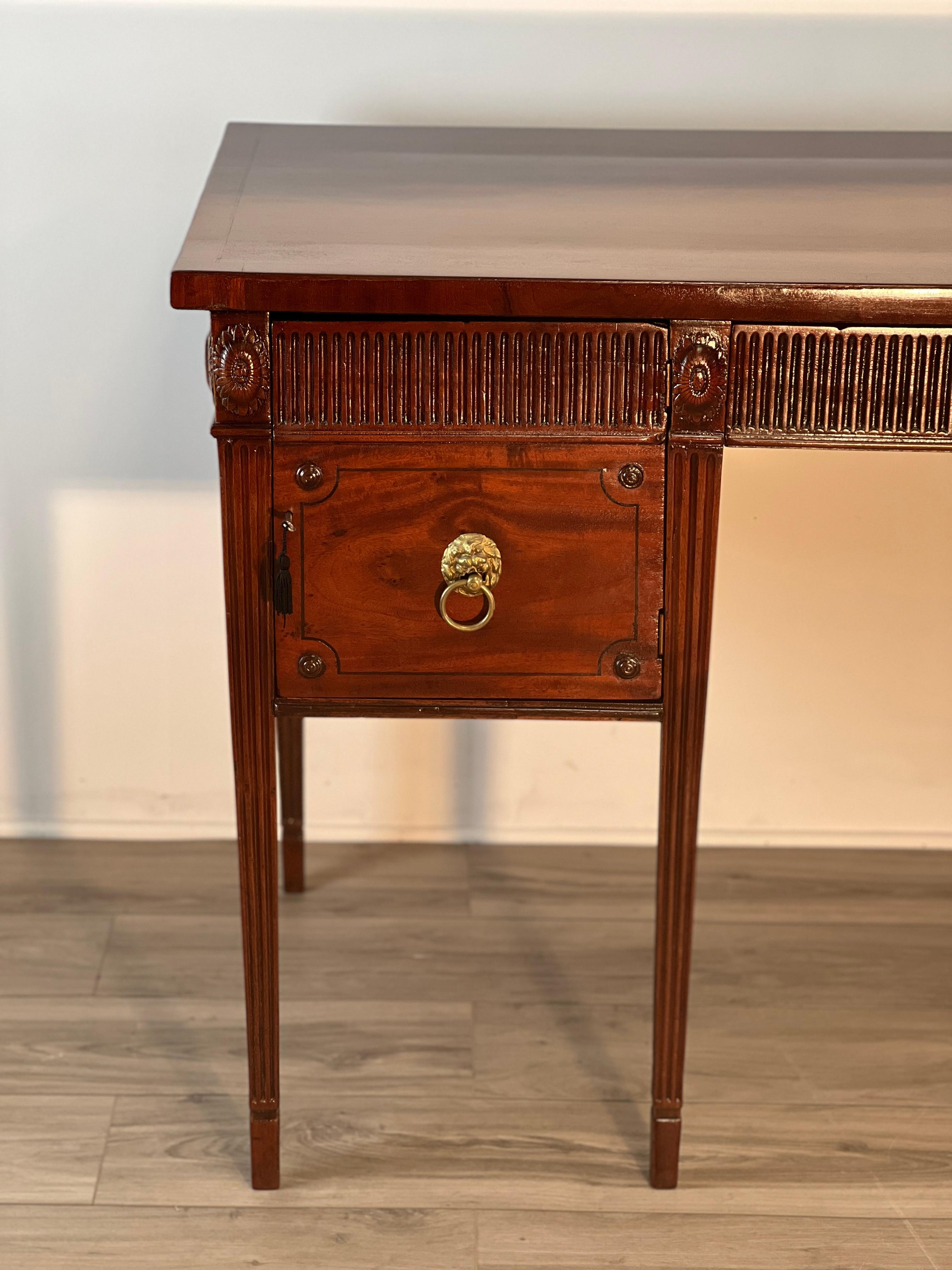 This is a late 18th century English George III hand made Mahogany side board. The handsome cabinet rests on top of six fluted legs with spade feet. The flamed mahogany panels on both the right and left side have been highly polished with lacquer.