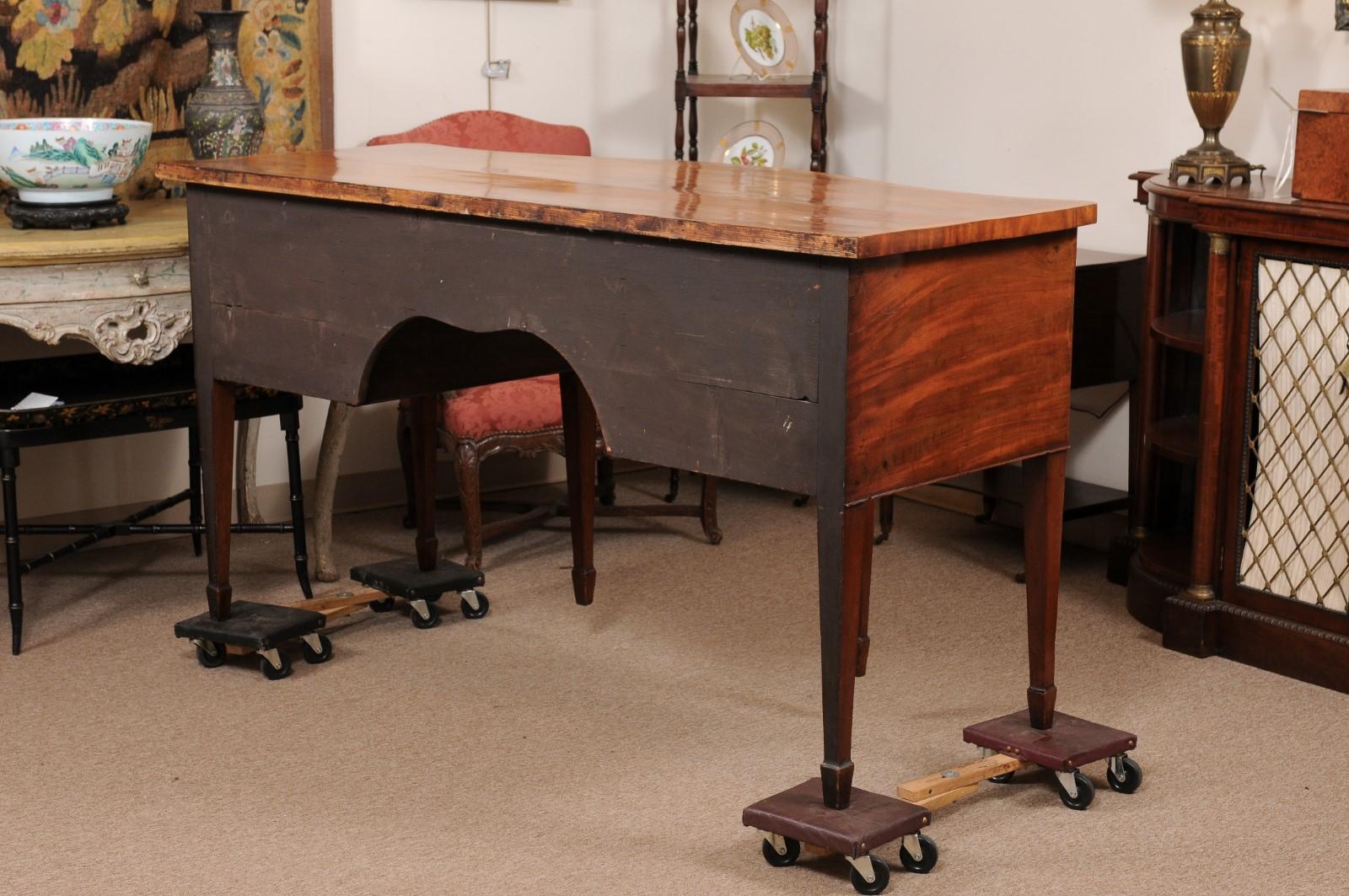A late 18th century English George III figured mahogany serpentine sideboard with string, cross-banding and fan satin wood inlay ending tapered legs with spade feet.