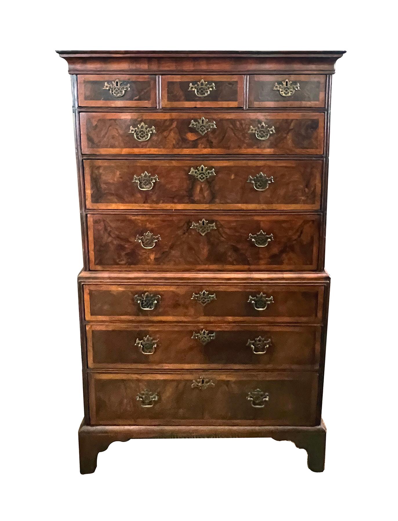 In two parts, the top section with molded crown over three short drawers above three graduated long drawers, the base with three long drawers all supported on bracket feet; later pierced brass bat pulls; crossbanded inlay to drawer edges