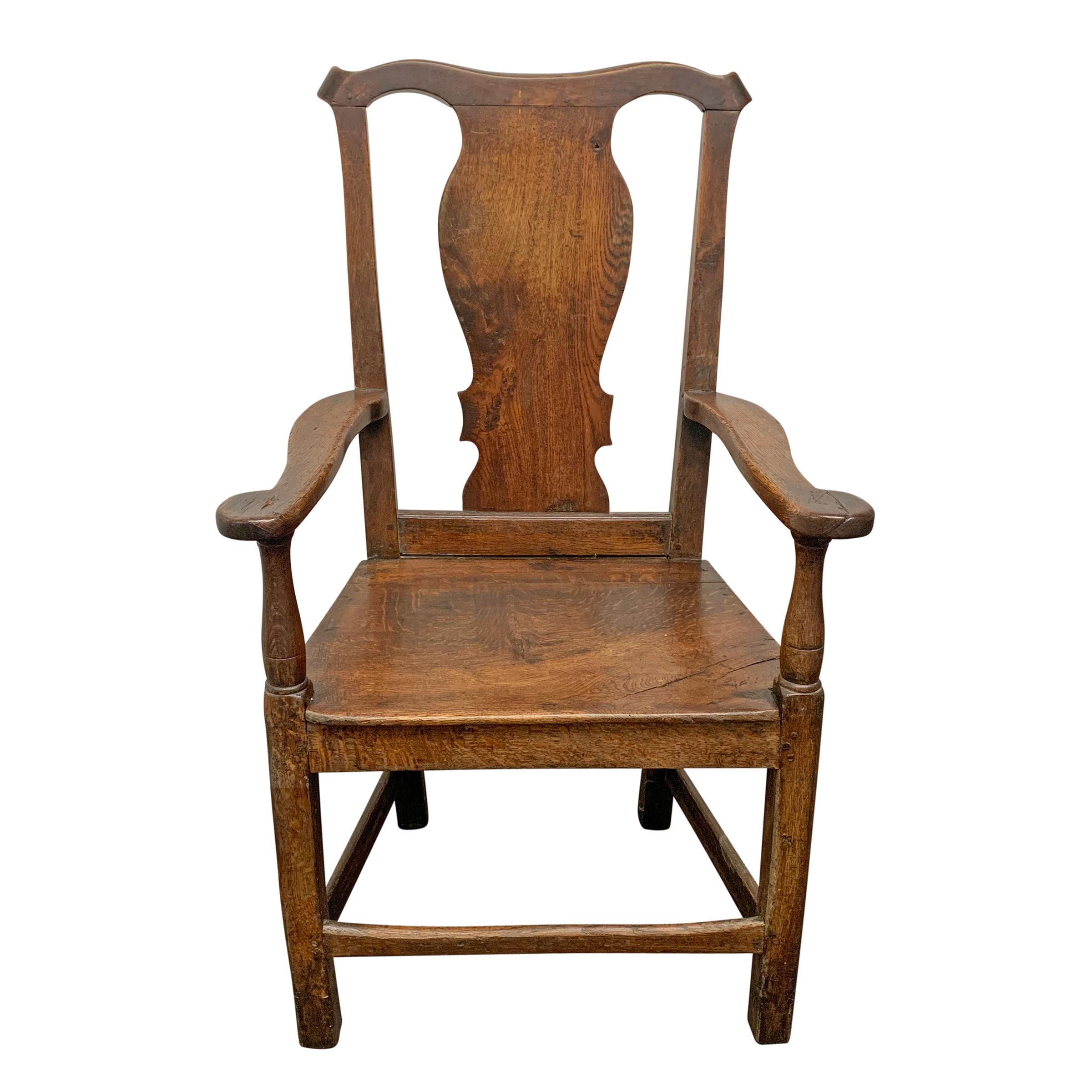 An incredible 18th century English oak Georgian chair with a wonderfully sculptural backsplat, a wide seat, and simple out-turned arms, and turned arm supports.