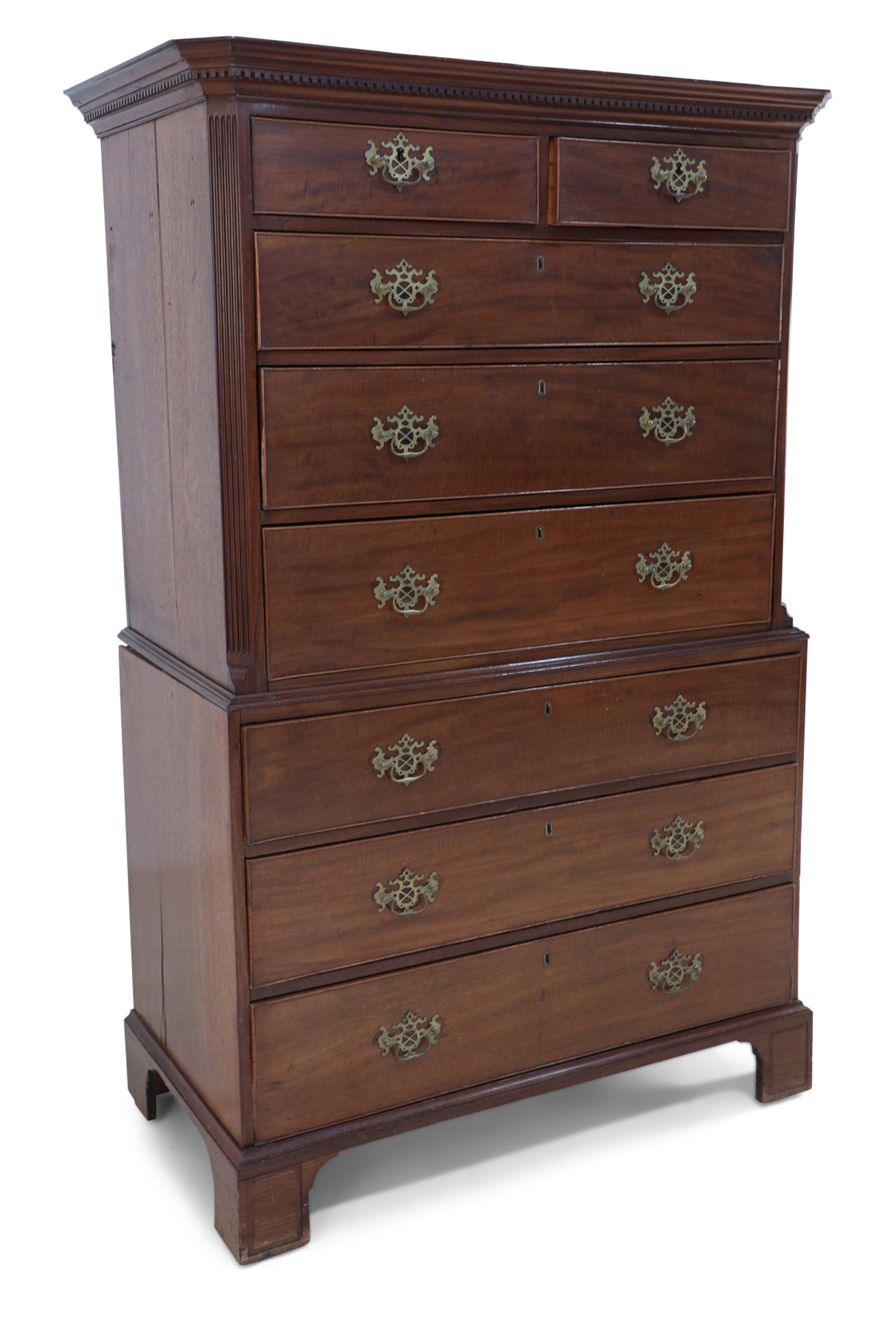 English Georgian (18th Century) mahogany chest on chest with eight drawers (two small, six large) having ornate brass drawer pulls, fluted detail on upper case, and a cornice with dentil carved detail and canted top corners resting on bracket feet.