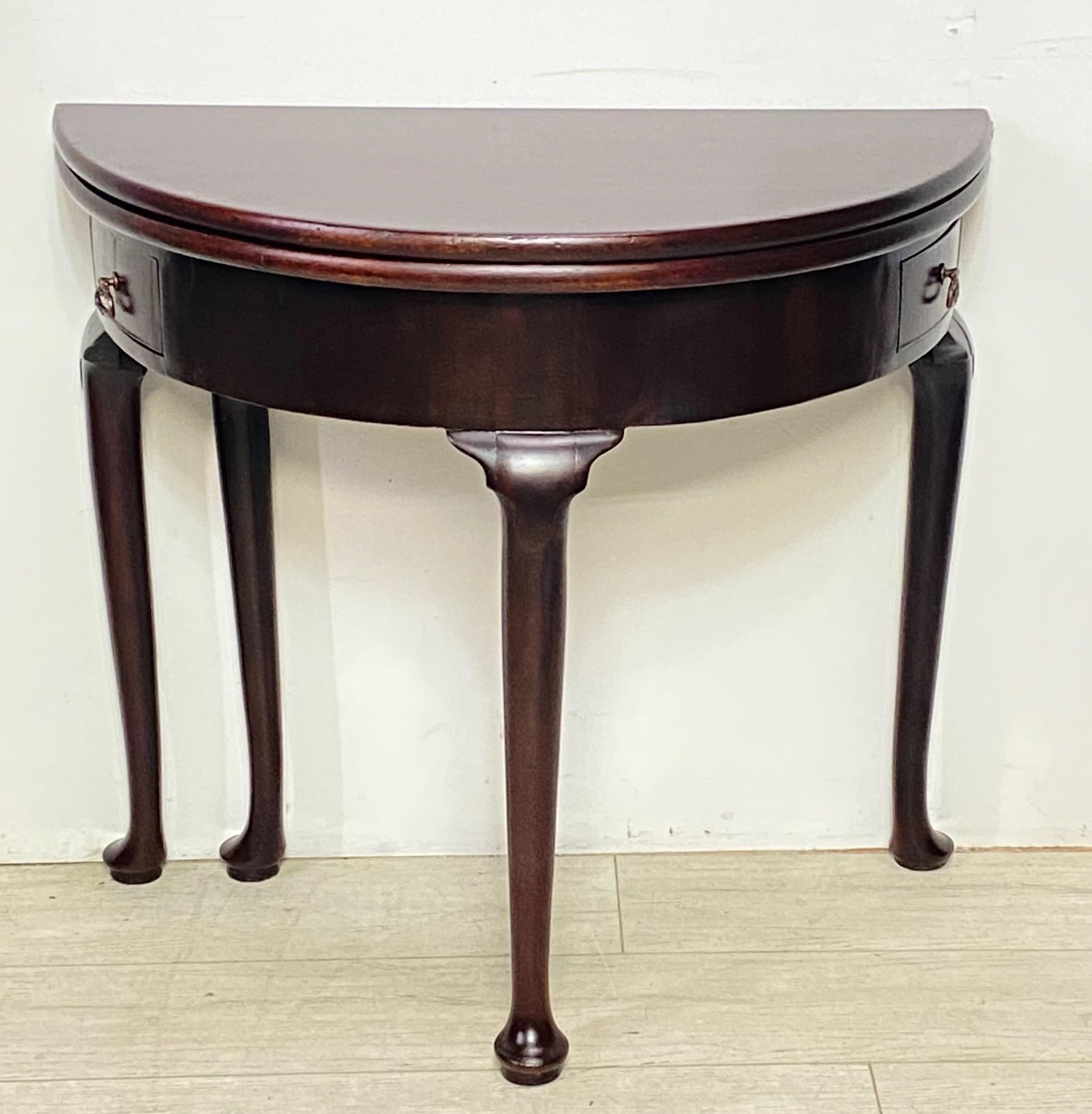 An 18th century Georgian period Demi Lune mahogany game / tea table with two small drawers. The top folds over and opens to a round table top supported on a swing out leg.
England, 1770-1780.
Recently refinished, the drawer pulls have been