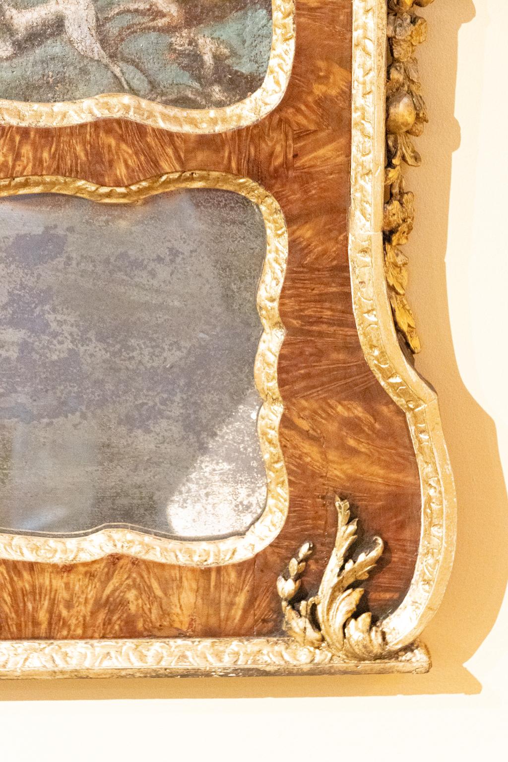 English Georgian 18th century mirror with oil on canvas hunt scene, circa 1780s. The mirror features Amboyna wood with gilt carved trim, new antiqued mirror, and re-gilded gilt trim. Made in England. Please note of wear consistent with age including