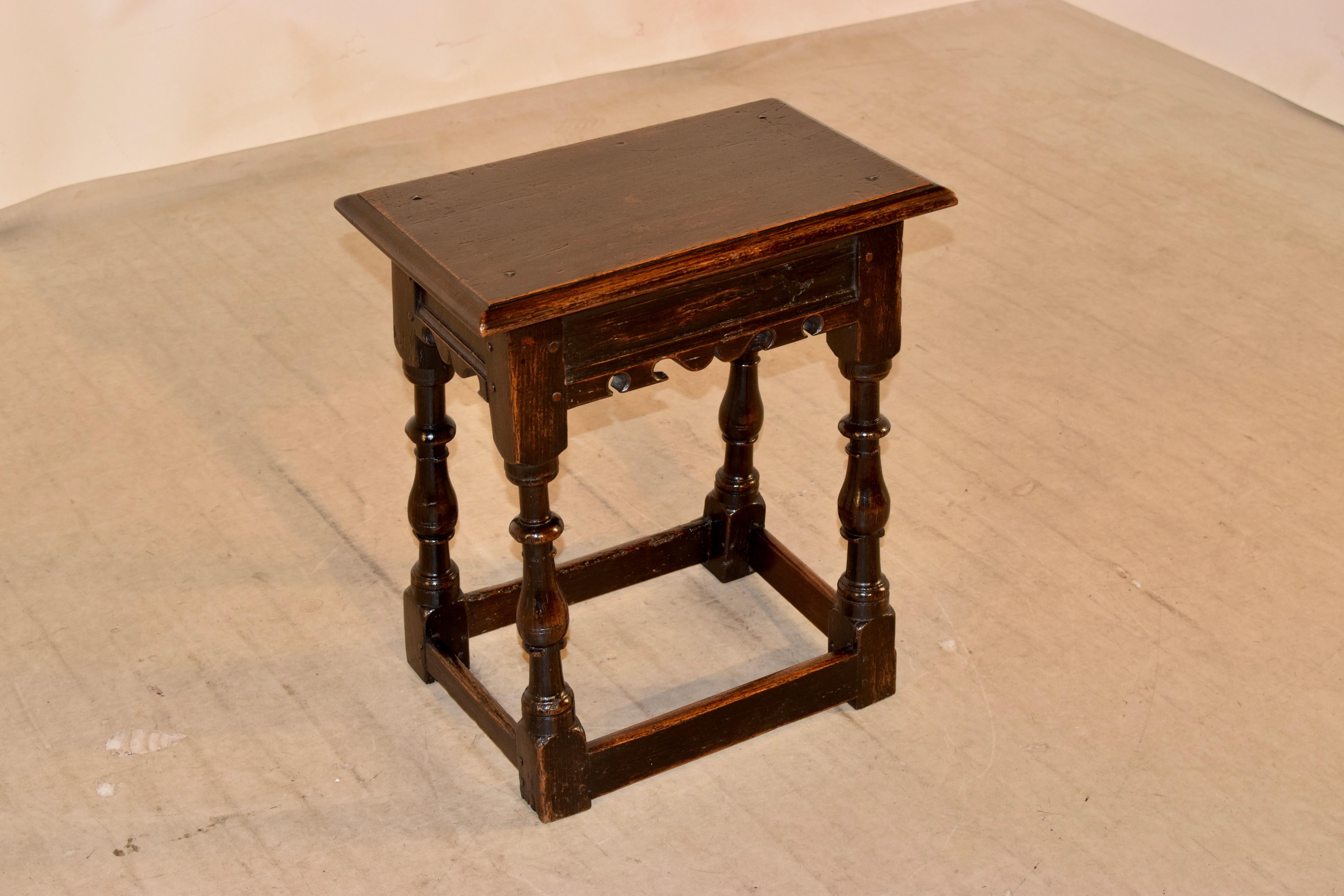 English oak joint stool with a beveled edge around the top and rose head nail construction, circa 1720. The apron is paneled and has scalloped edges following down to wonderfully turned legs joined by stretchers, which are worn from use.