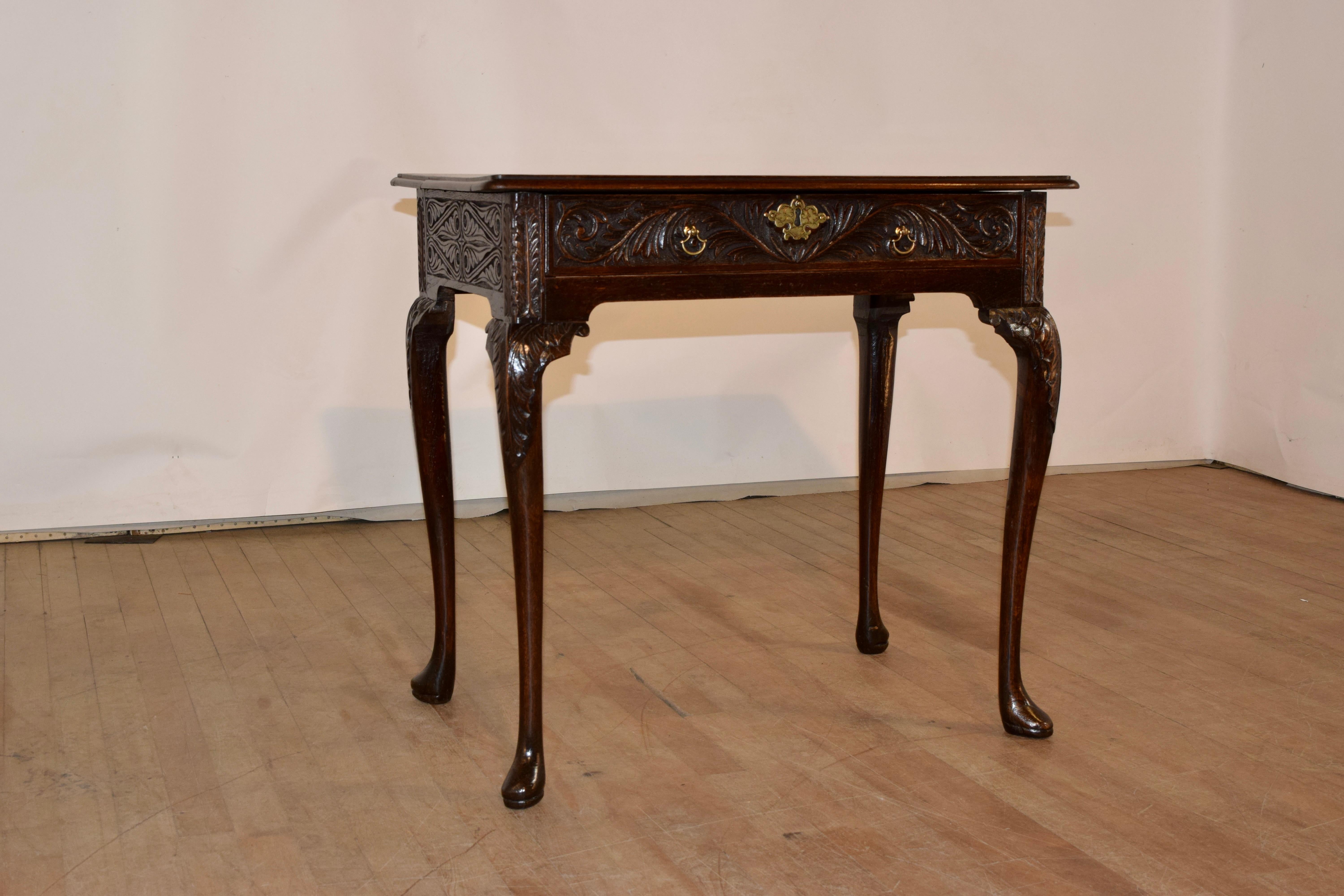 18th Century oak lowboy from England with an Ash top, made from two boards. The top is pegged construction and has a beveled edge, following down to an exquisitely hand carved oak base, with decorated sides and a single drawer in the front, also