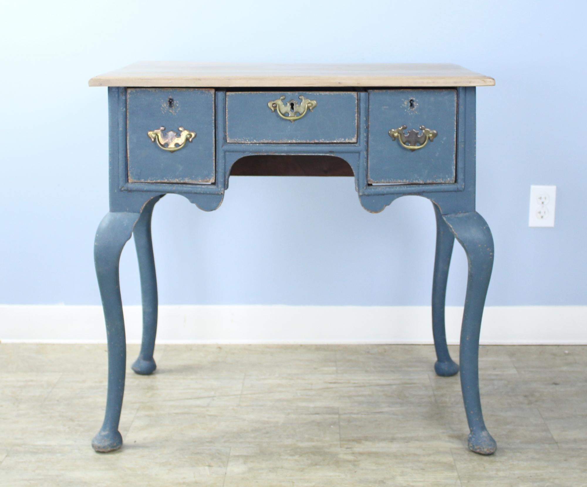 An early country padfoot lowboy, with all of the graceful elements of its type, newly painted in a cool blue and faux distressed for a vibrant modern look. The top has been bleached to complete the picture. An antique Silhouette made eye-catching