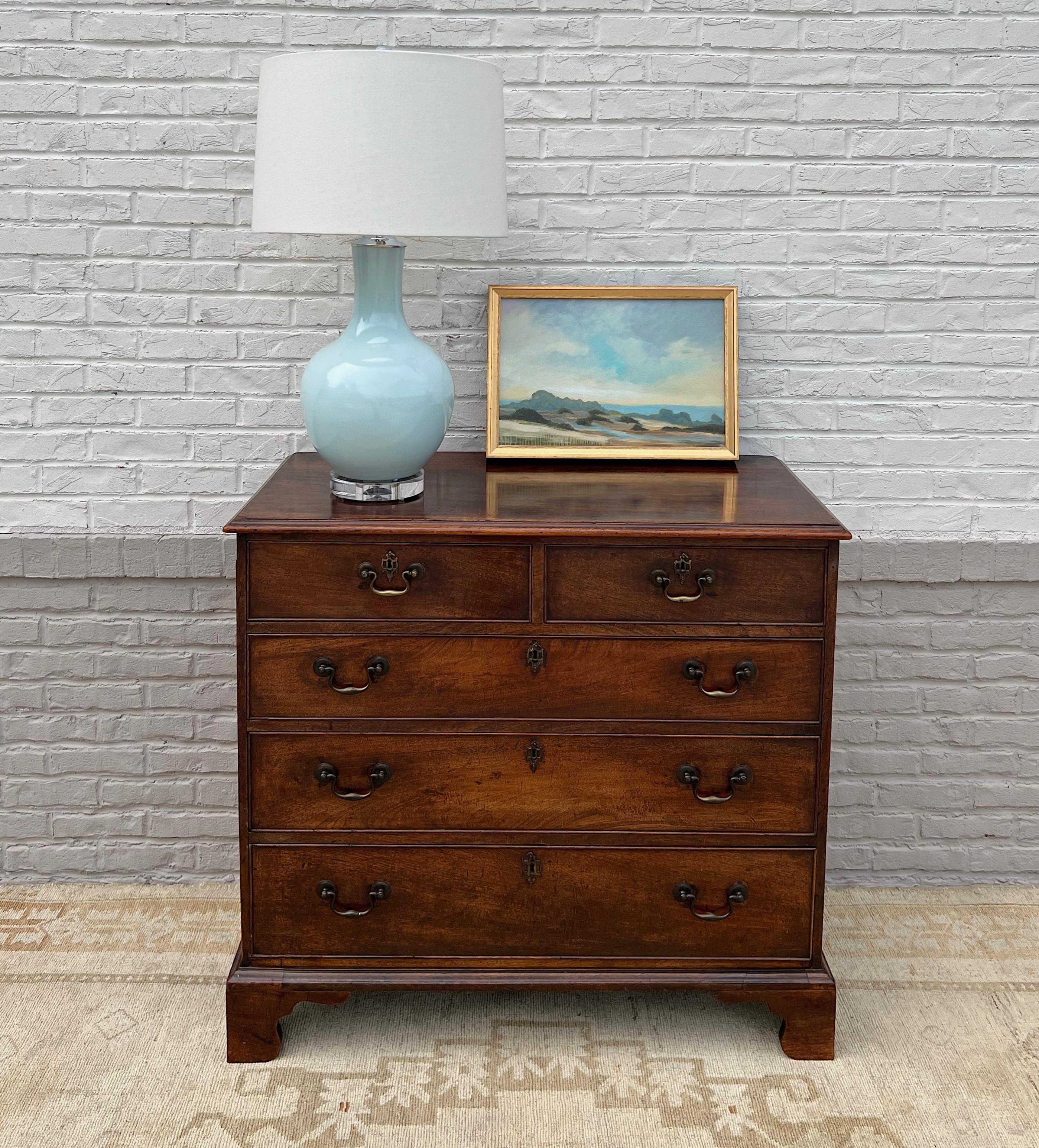 An elegant 18th century English country mahogany chest of drawers with beautiful coloring. Handsome swan-neck brasses and escutcheons adorn the five dovetailed drawers. Standing on graceful bracket feet. A truly beautiful antique that will be