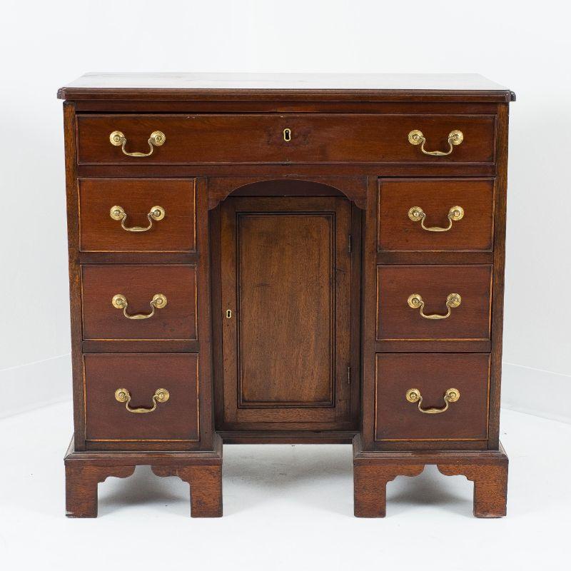 English Georgian Cubus mahogany knee hole vanity or dressing table. The top has a molded edge with dimpled front corners which rests on a long, single drawer over mirrored stacks of three drawers, resting on bracket feet and flanking a recessed wig
