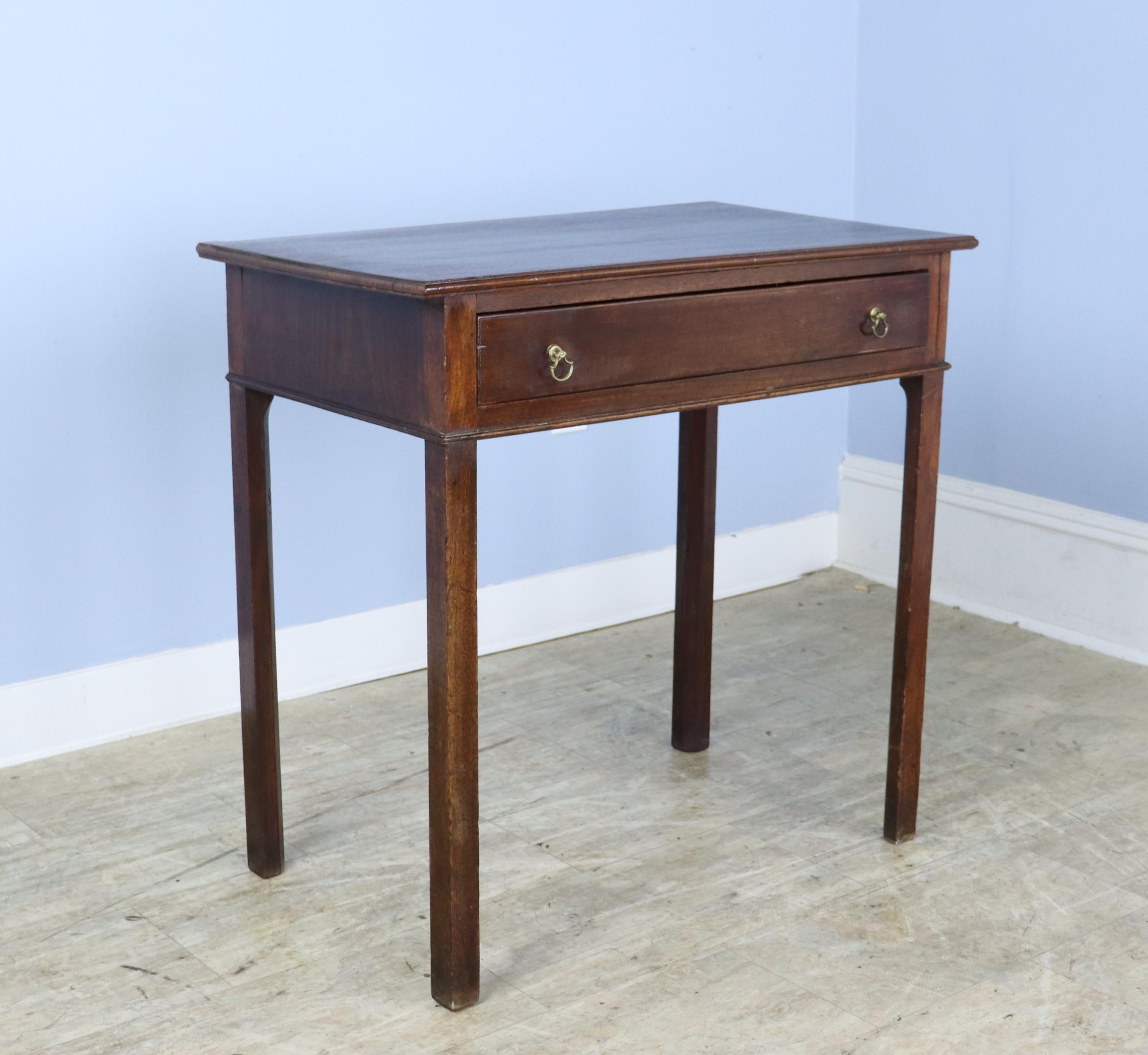 An antique occasional table from England. Classic Georgian shape. Mahogany with a rich grain and patina. One wide drawer with classic brass handles under carved edge. Would make a suitable lamp table. Top has been lightly refinished. but some slight