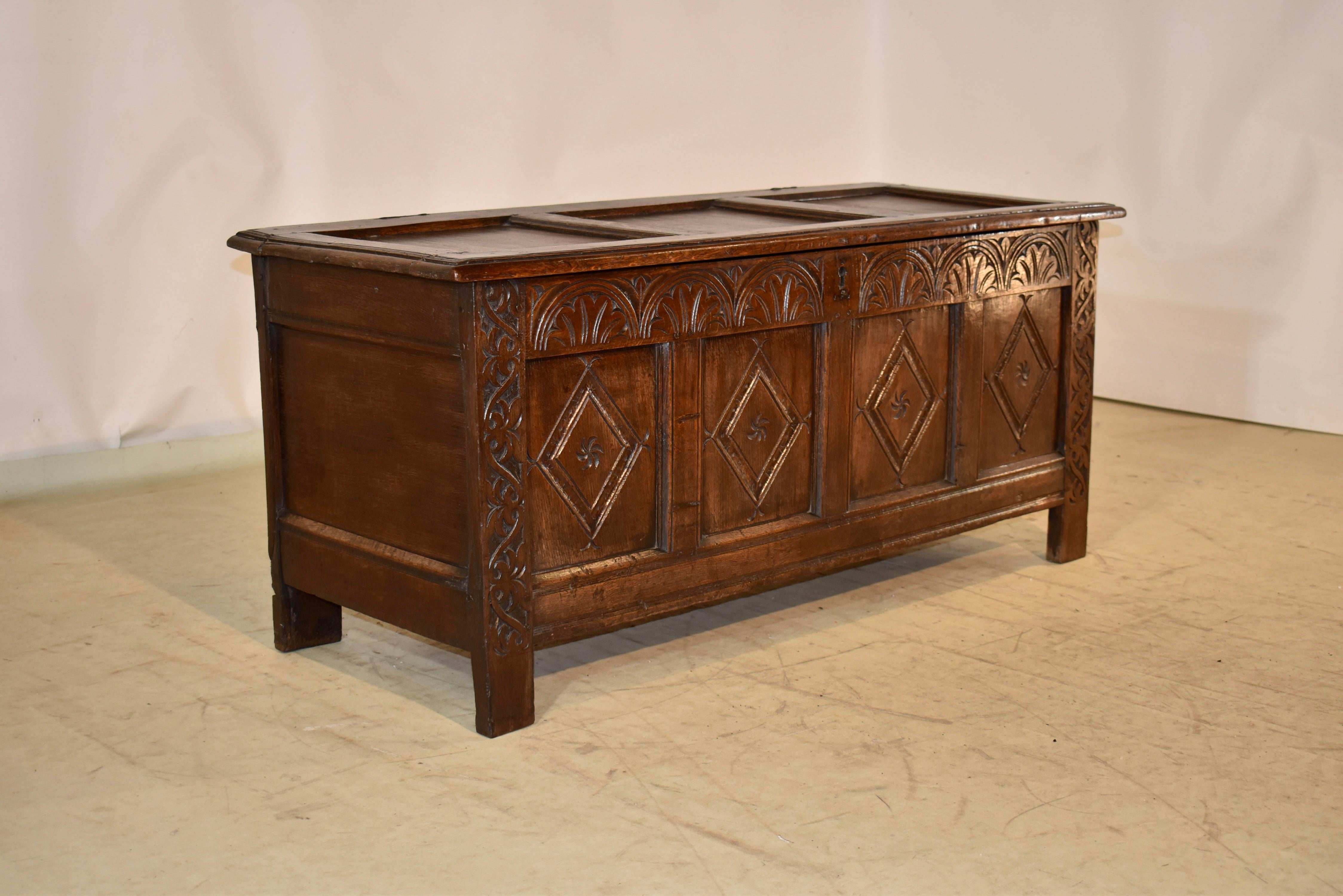Early 18th century oak blanket chest from England.  the top has three panels, surrounded by a frame with a beveled edge.  The front of the case has four panels which have hand carved designs.  There is a carved panel above the four panels and the