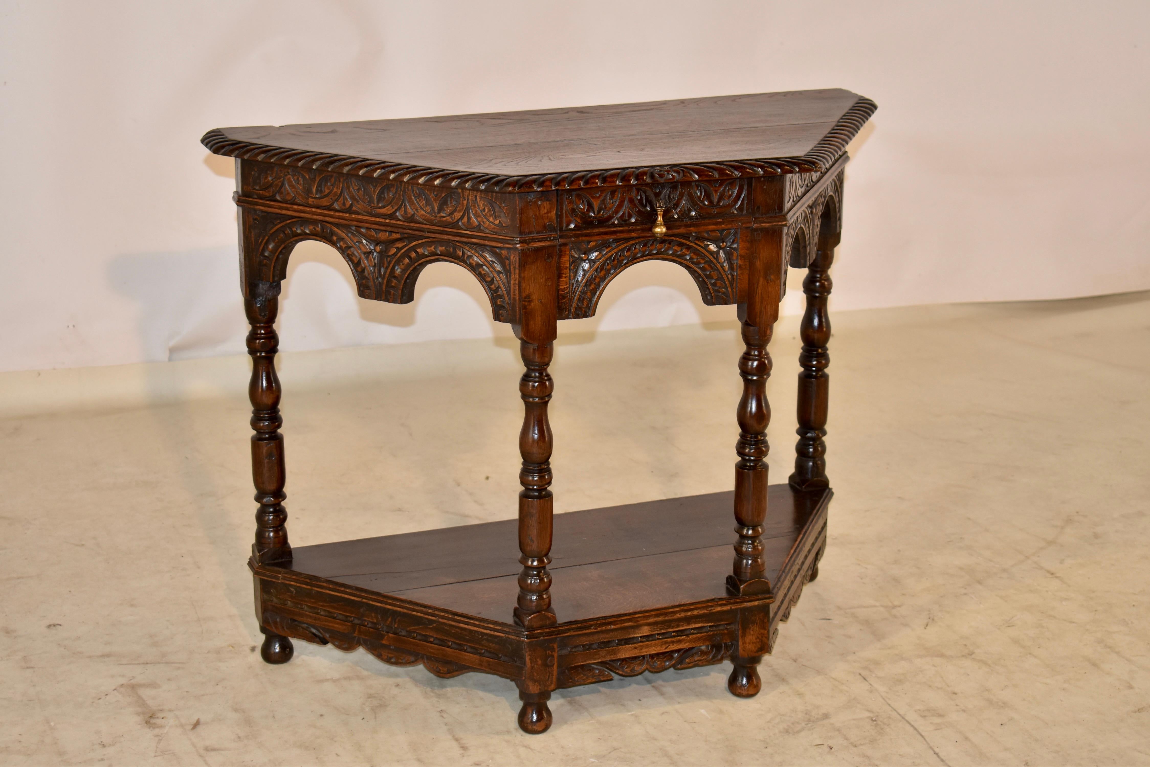 18th Century oak console or side table from England. The table has a two plank top with a hand carved and beveled edge, following down to a wonderfully hand carve decorated apron which is hand scalloped and has lovely arched details as well. The
