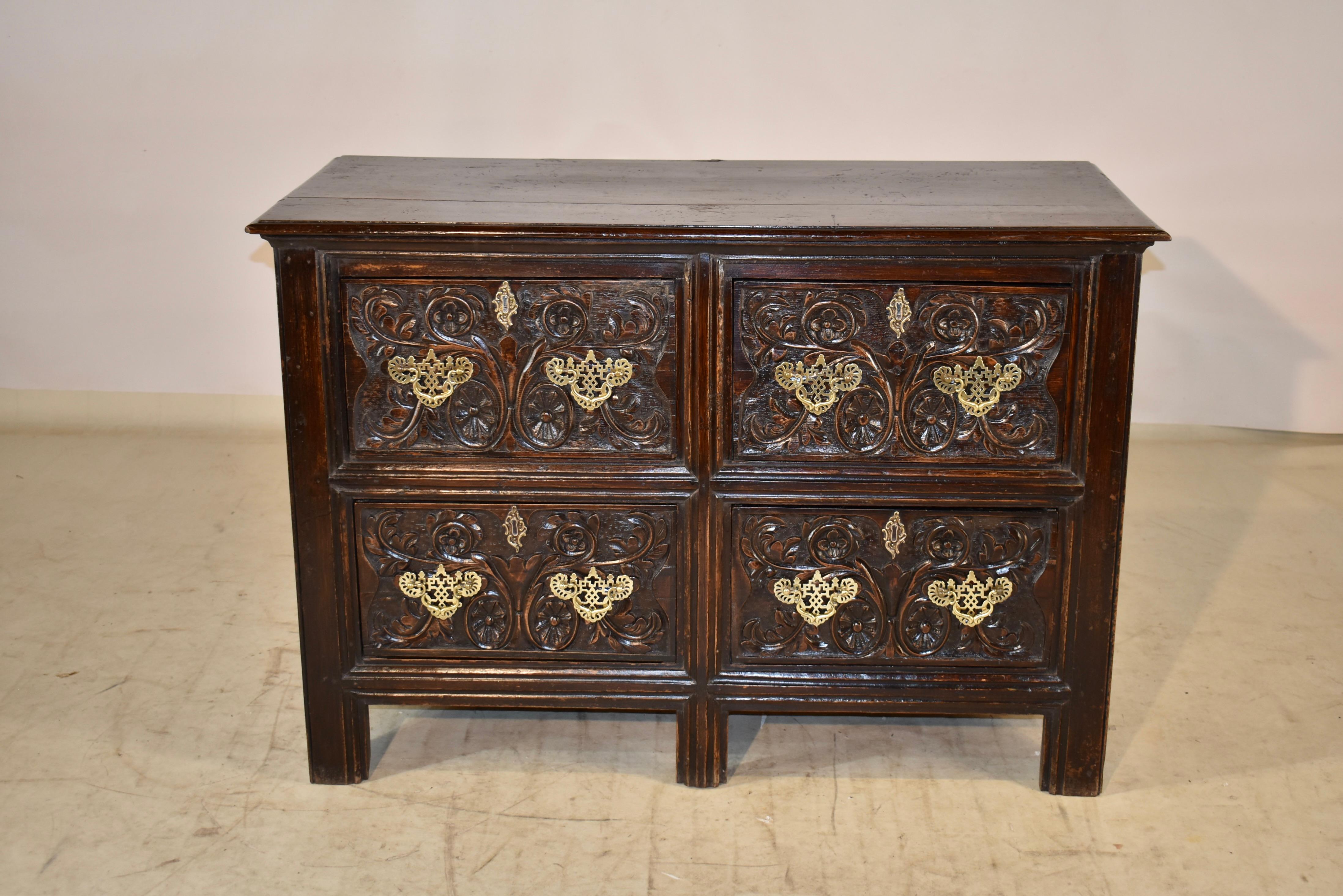 18th century Unusual English chest of drawers made from oak. The top has a beveled edge, and follows down to simple paneled sides, which add design interest from the side of the piece. the front contains four drawers, all with hand carved