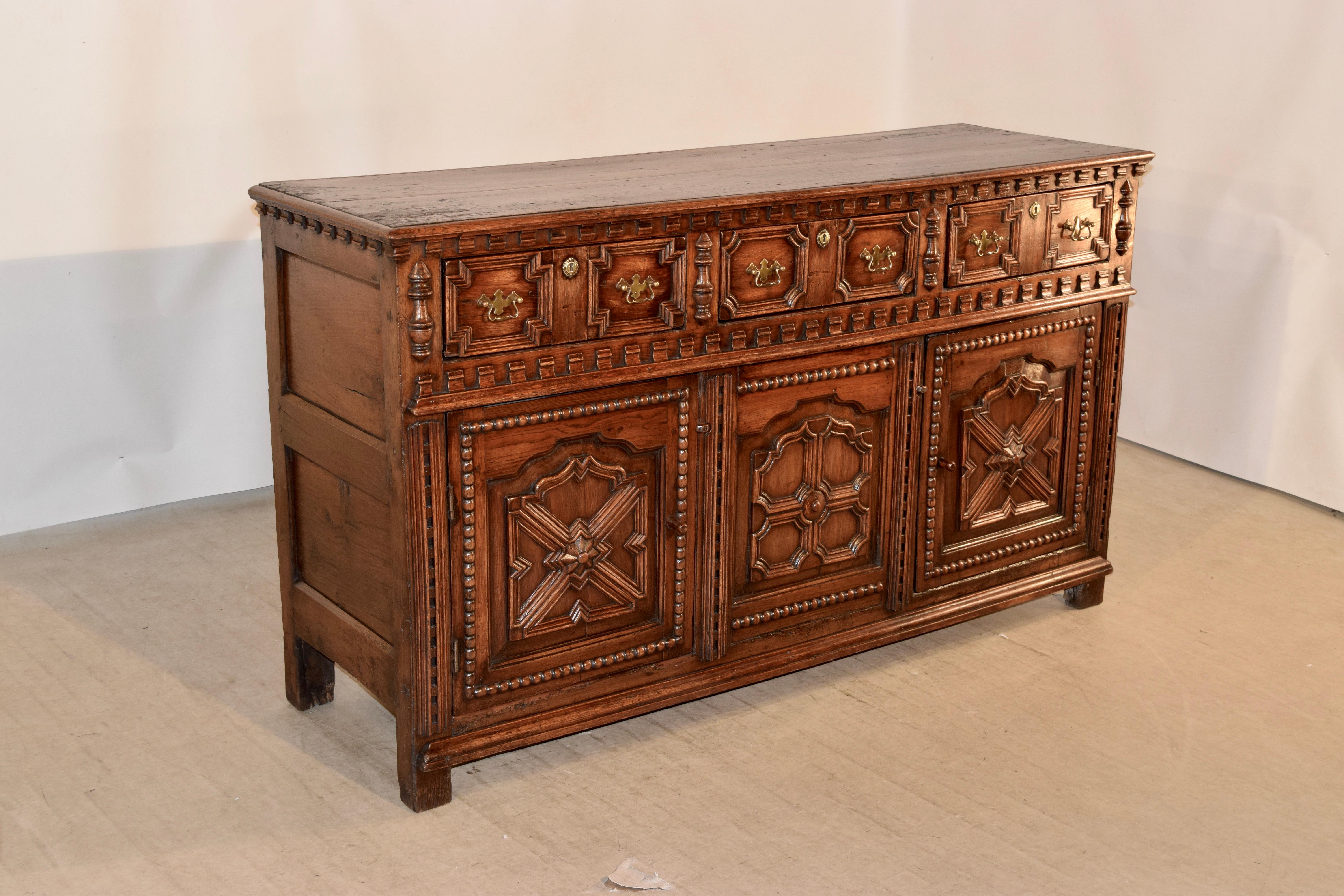 18th century English oak dresser base with a two plank top which has a beveled edge, following down to wonderful dentil detail over simple paneled sides and three drawers in the front, which are decorated with molded panels and flanked by applied