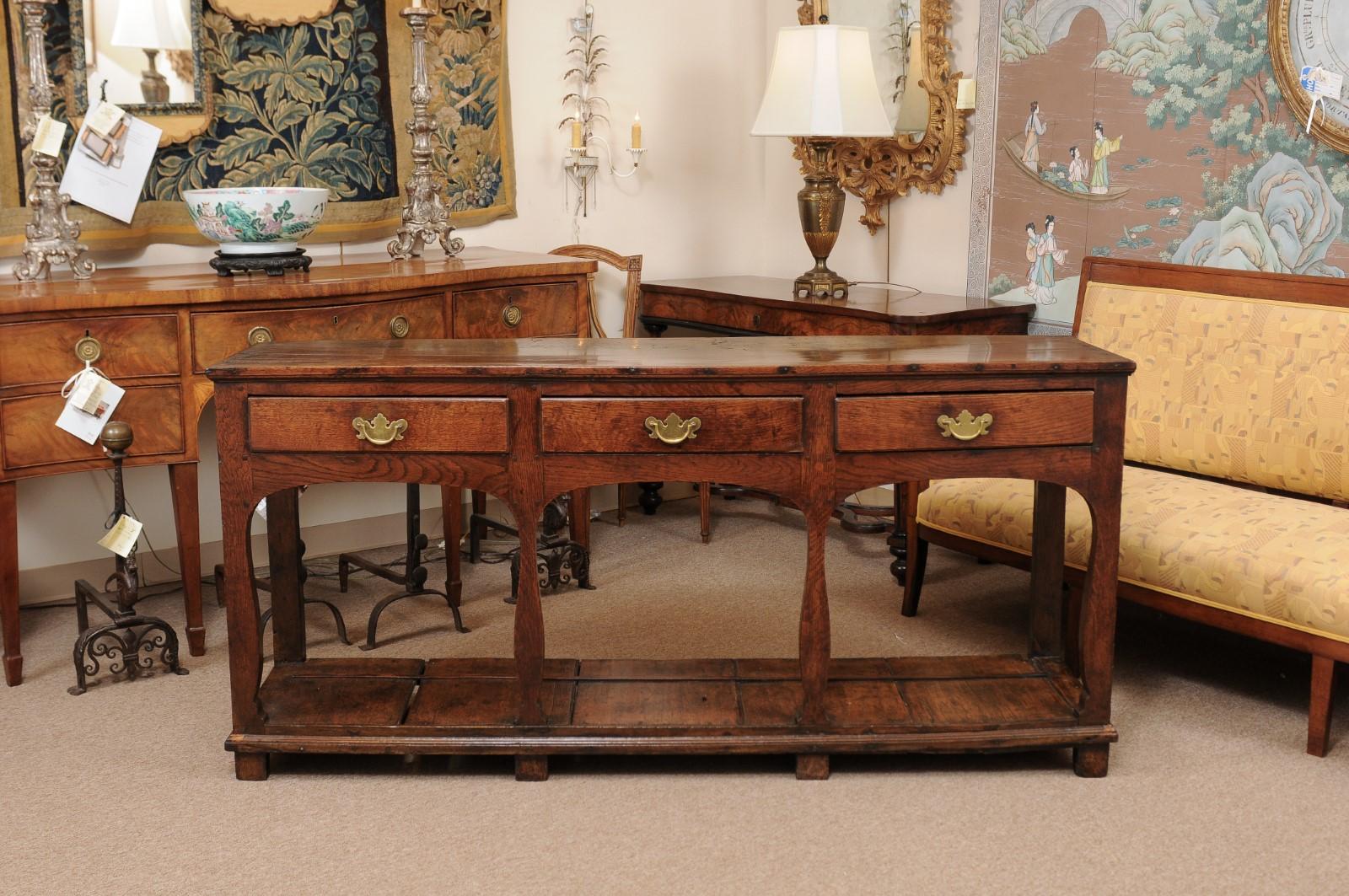 A dresser base/server dating from the 18th century and English in origin. The server constructed in oak with 3 drawers in frieze with 4 shaped front legs and 2 straight back legs joined by plinth base ending in square feet.

  