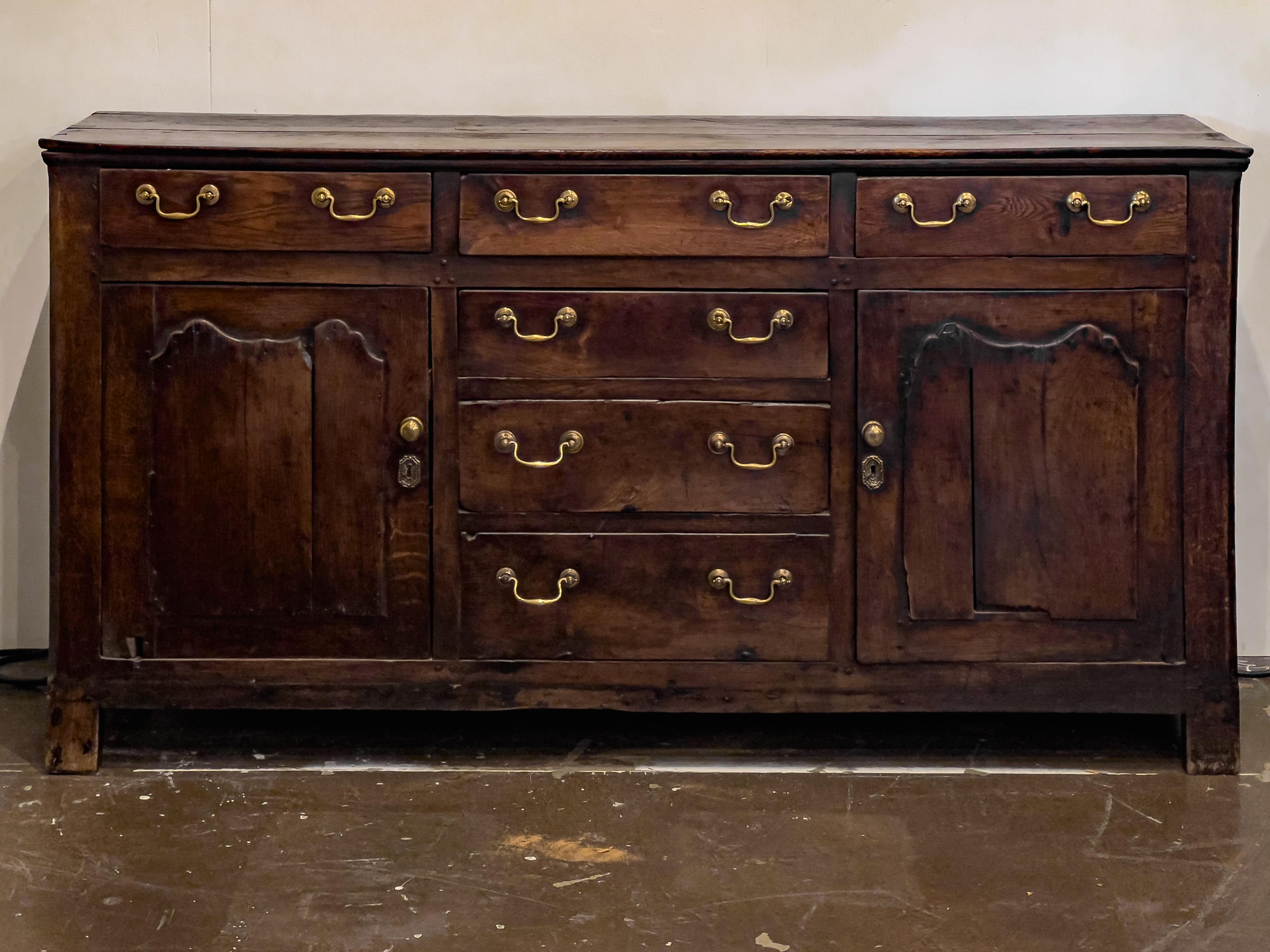 18th century English oak dresser with two doors and four functional drawers (two false drawers on the bottom) with drop bail hardware.