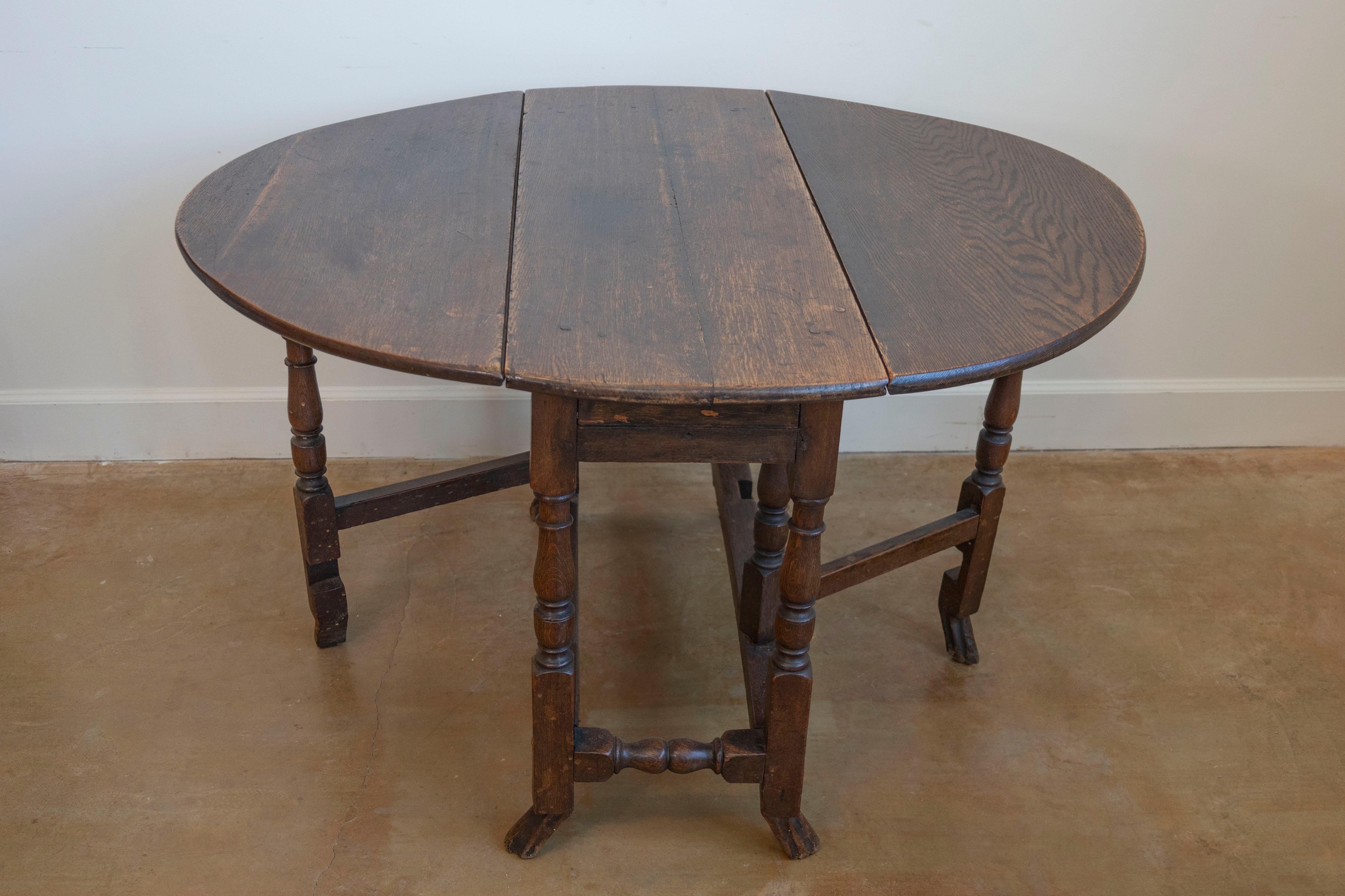 An English 18th century oak oval gateleg drop-leaf table with unusual drake feet. Born in the second half of the 18th century, this English gateleg table features an oval top made of two drop leaves, sitting above a nicely turned base with side