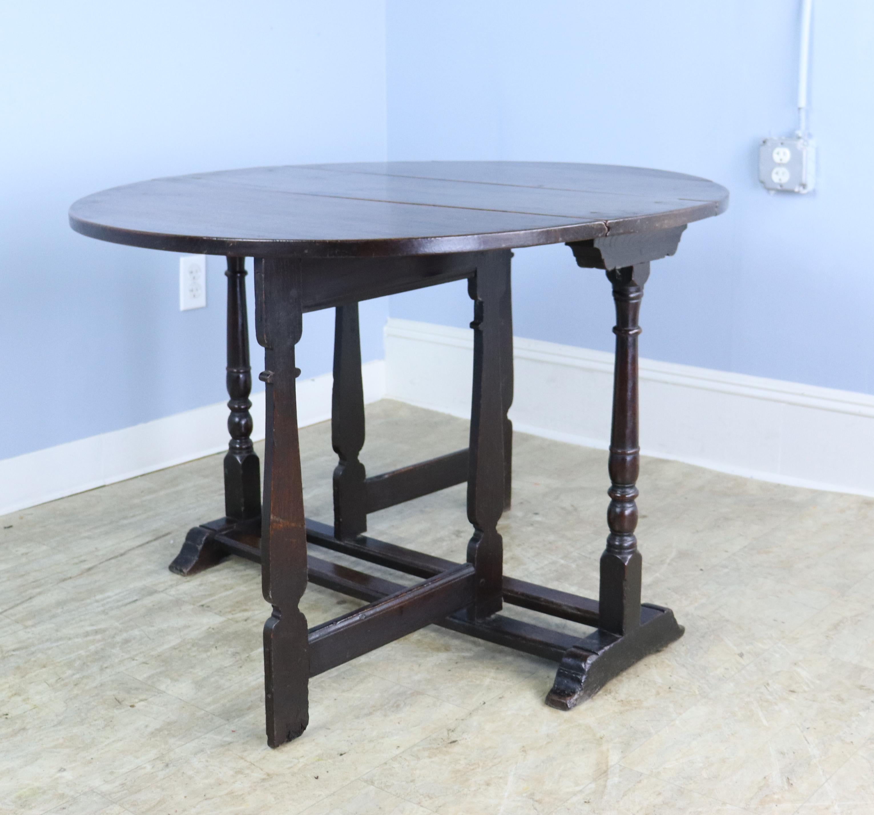 The top of this early oak table is a good size occasional or breakfast table in original condition. This is an example of a very early gateleg, with well proportioned drop leaves and a good folding mechanism. The color is a nice warm oak. Seating