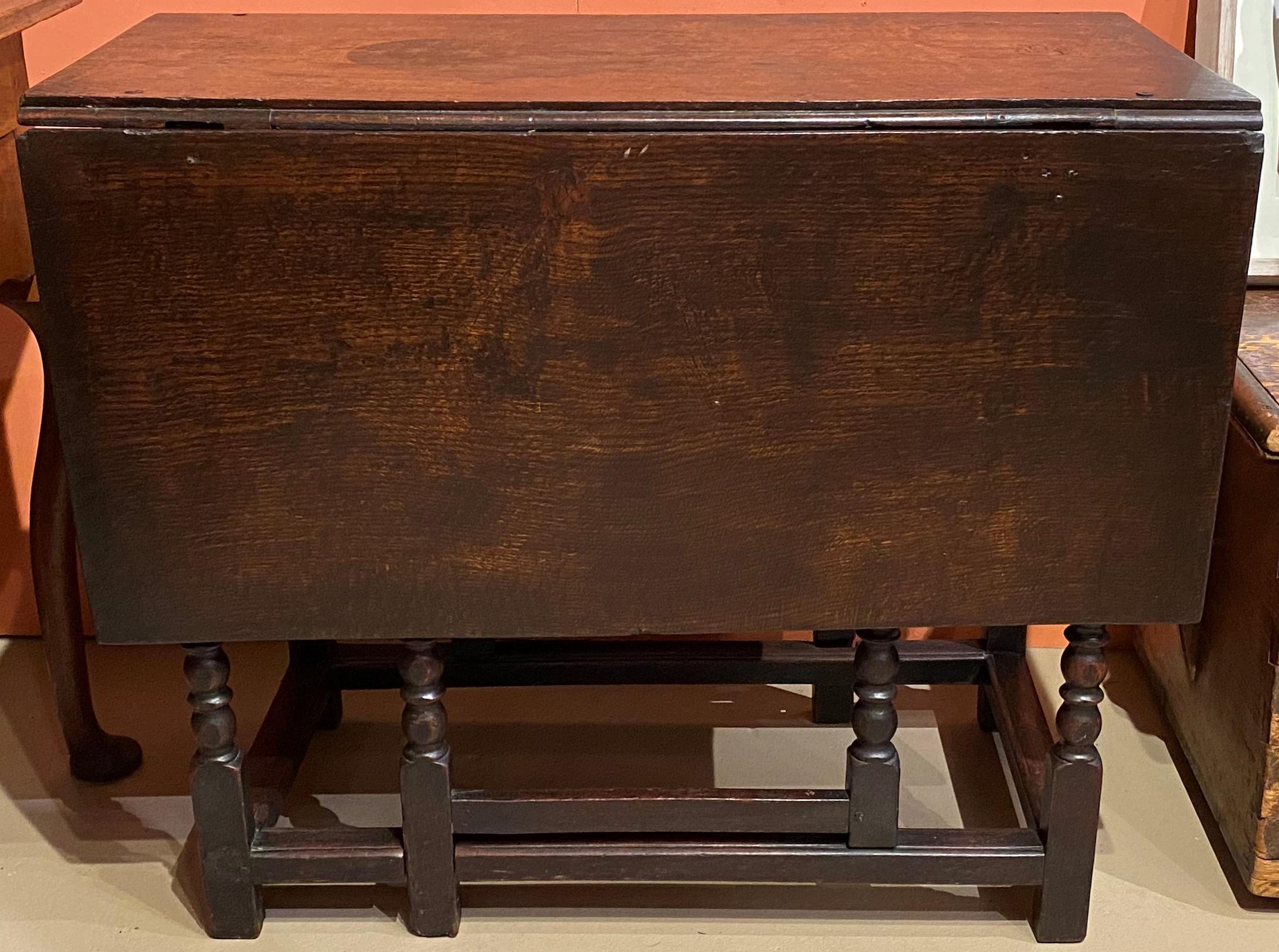 A fine example of an 18th century English oak drop leaf gateleg table with nice turned legs, and a swing gate leg on each side, along with a stretcher base. The table has probably retained its original surface in very good condition, with some small