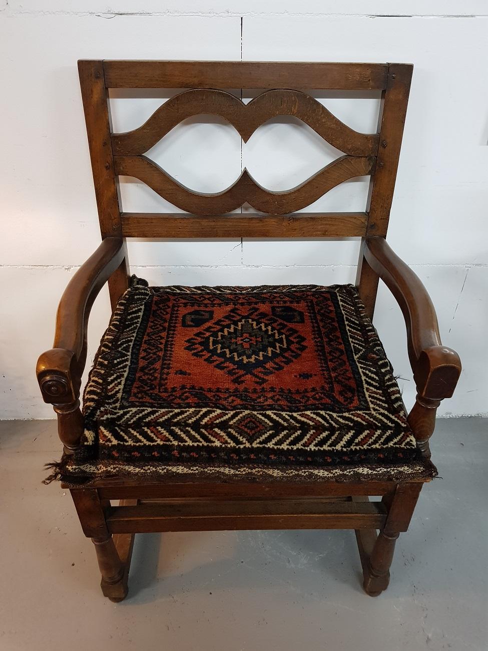 Beautiful minimalist designed English oak armchair from the 19th century with an open back and the legs connected with a stretcher, with a persian wool pillow from the 20th century.

The measurements are,
Depth 54 cm/ 21.2 inch.
Width 65 cm/ 25.5