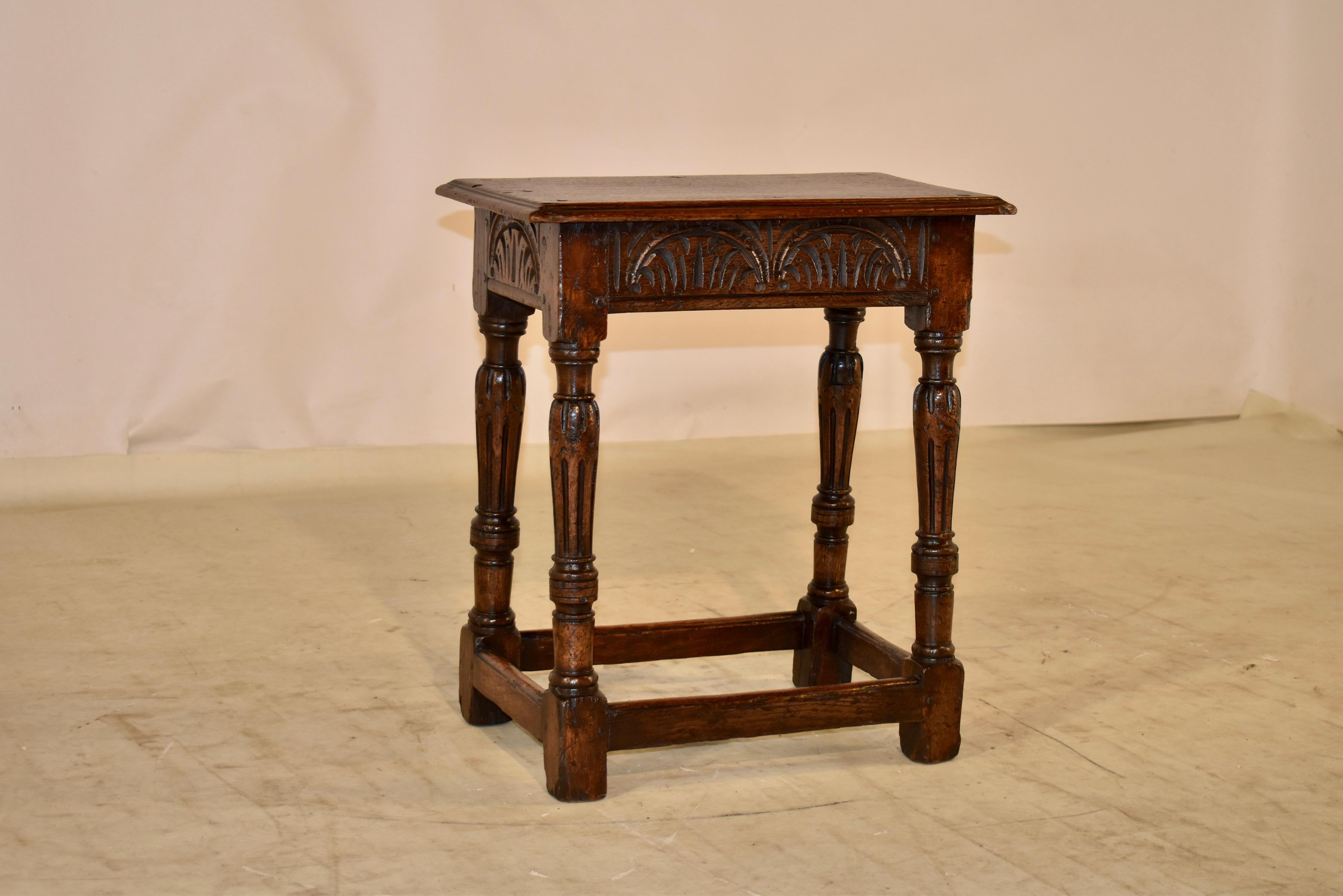 18th century oak joint stool from England. The top has a beveled edge and has pegged construction. The top follows down to a hand carved apron, over splayed and hand turned and carved legs, joined by simple stretchers. This piece has extraordinary