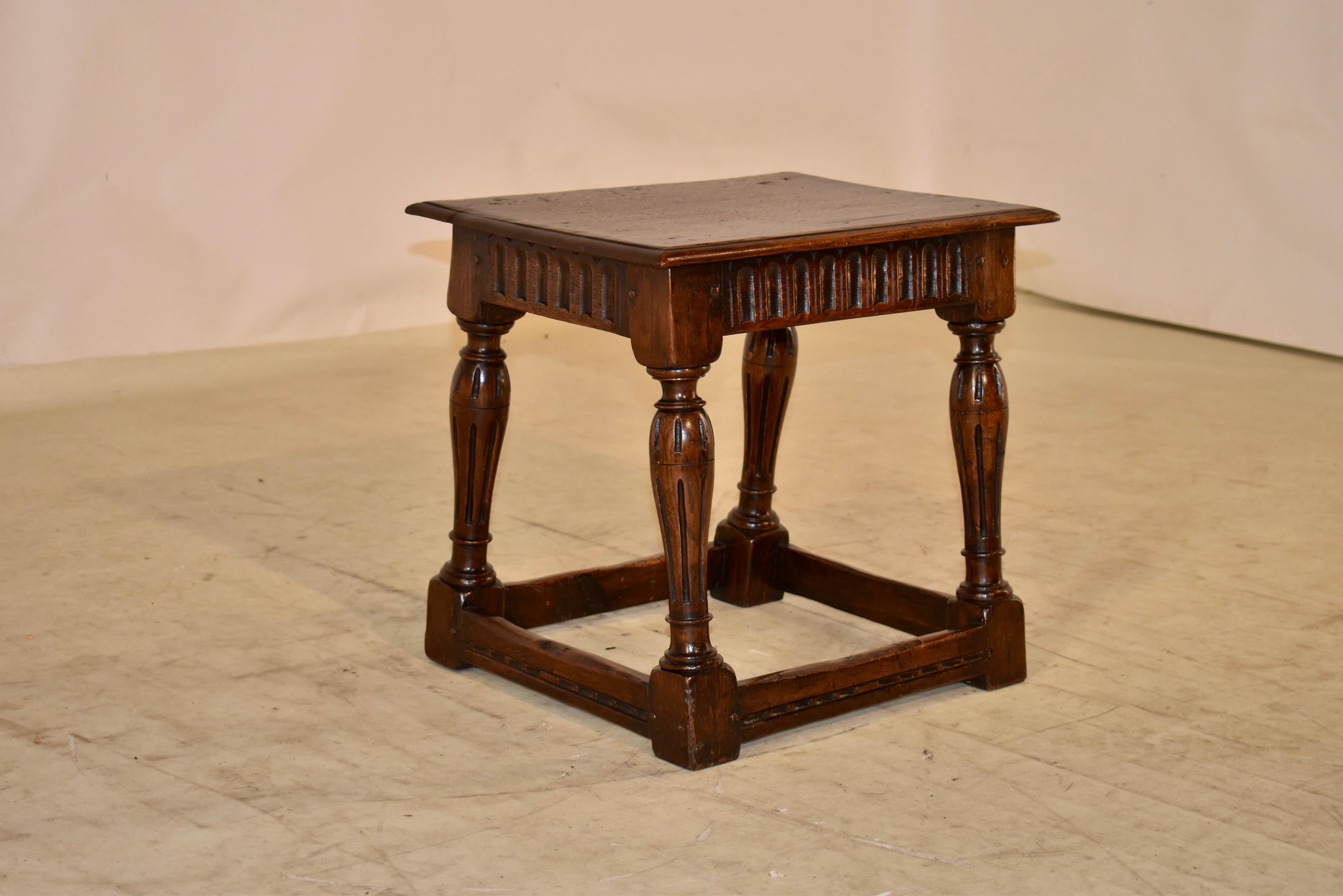 18th century oak joint stool from England with a single plank top with pegged construction. This follows down to a hand carved apron with nulling decoration and supported on hand turned and slightly splayed legs. The legs are fluted as well, and are