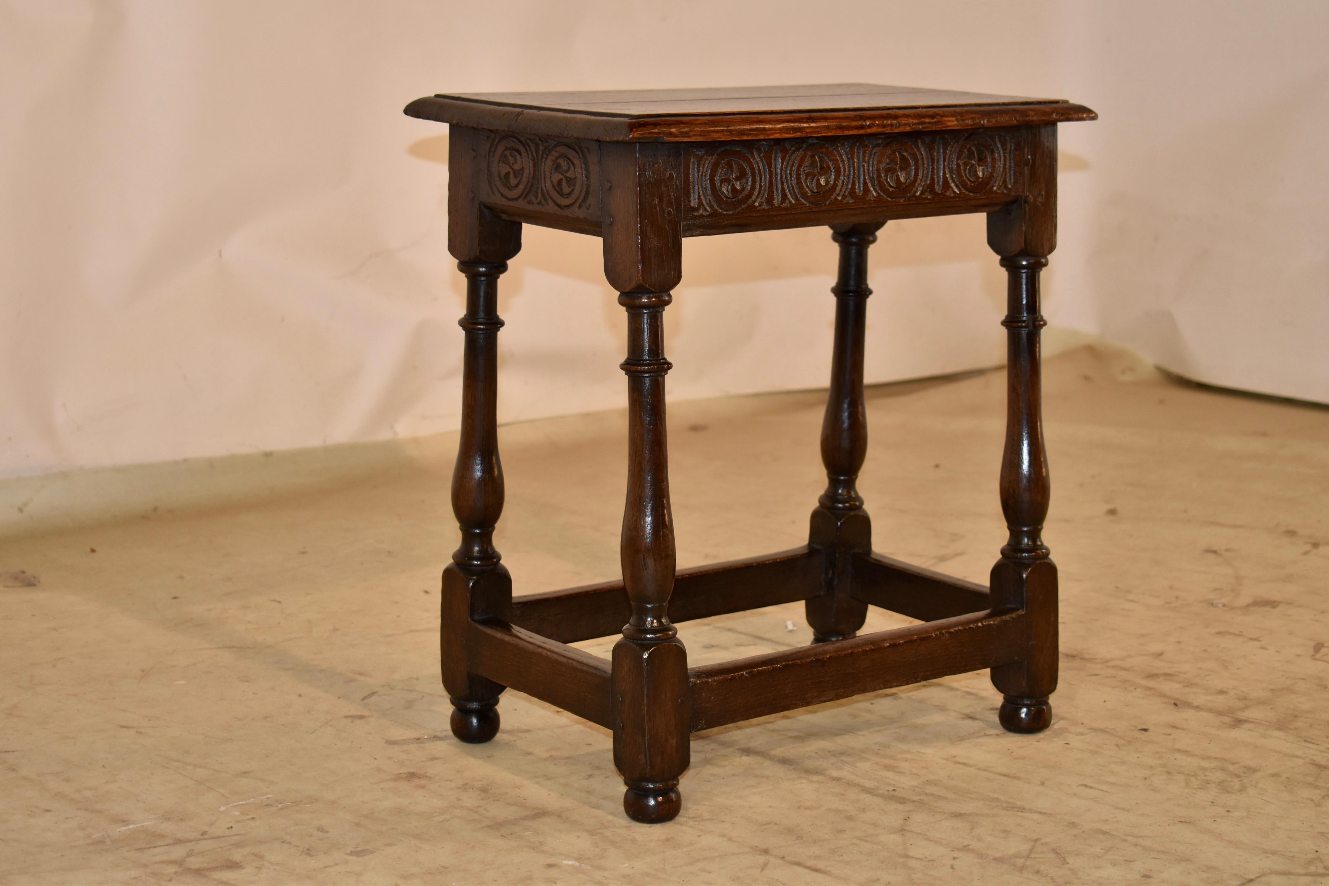 18th century oak joint stool from England.  

The top is pegged and has a beveled edge, following down to a lovely hand-carved decorated apron featuring encircled fylfots, which are symbols for prosperity and good fortune.  

The stool is supported
