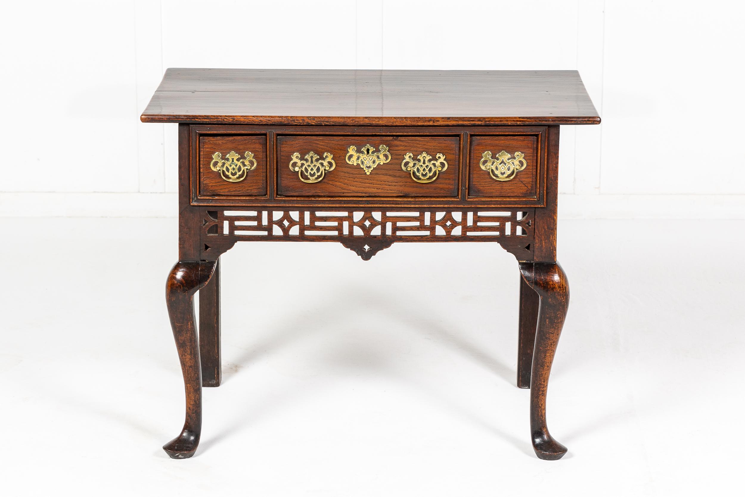 Superbe bas de caisse en chêne anglais du XVIIIe siècle, avec un dessus en planches et trois tiroirs profonds en dessous, avec des écussons en laiton percés et des poignées en forme de goutte d'eau. Un tablier avant exceptionnellement sculpté et