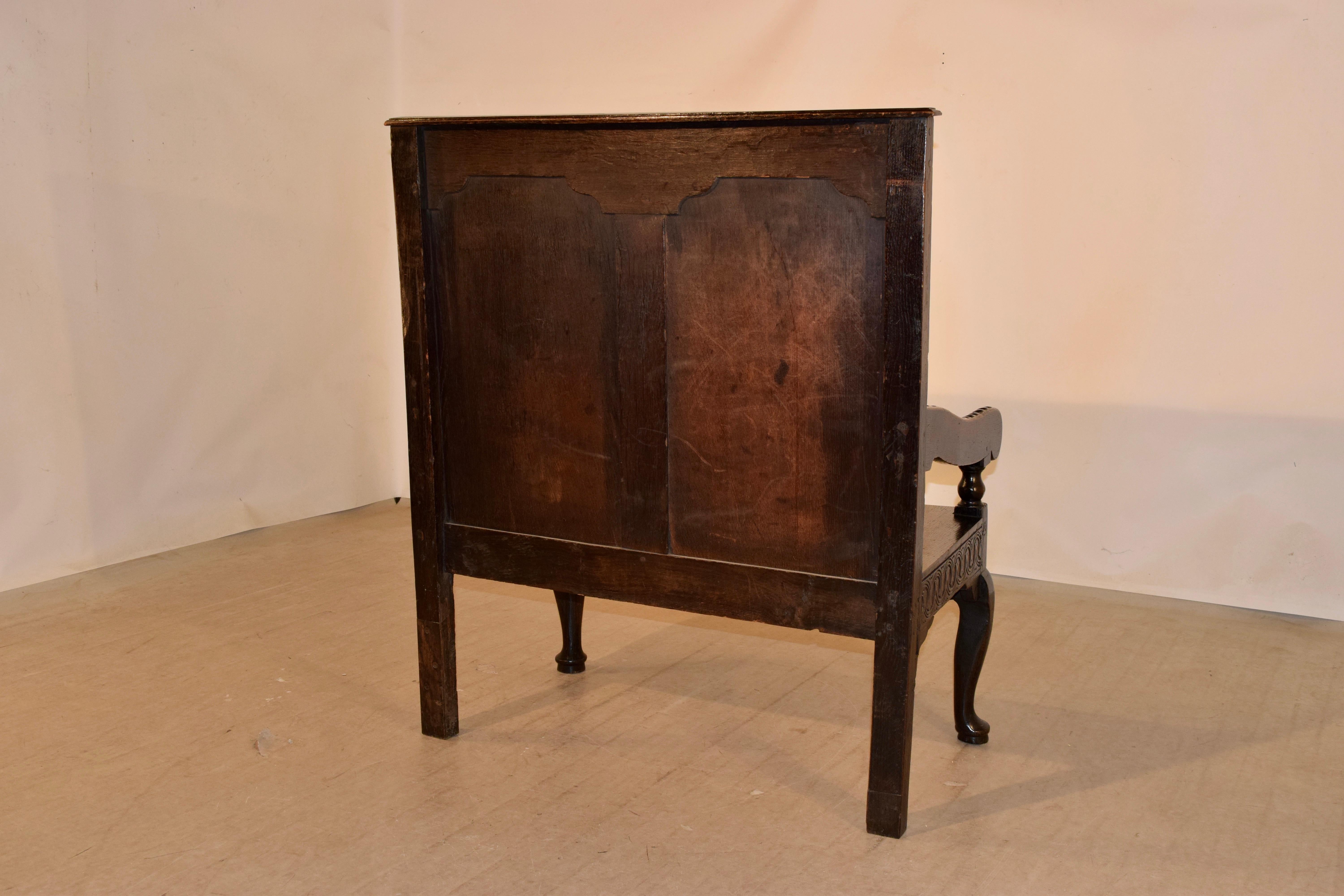 18th century English oak settle with a molded edge at the top following down to a hand carved border with two large hand carved panels in the back, supported on a base with hand carved aprons and simple legs in the back for easy placement against a