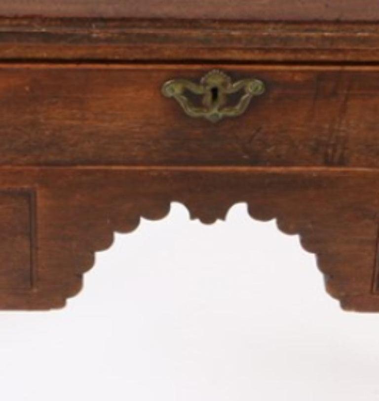 An 18th century English side table with a rectangular top and molded edge featuring rare double incurved corners. Upper beaded long top drawer over two lower drawers surrounding a scalloped arch to central apron. Useful size in a living room or for