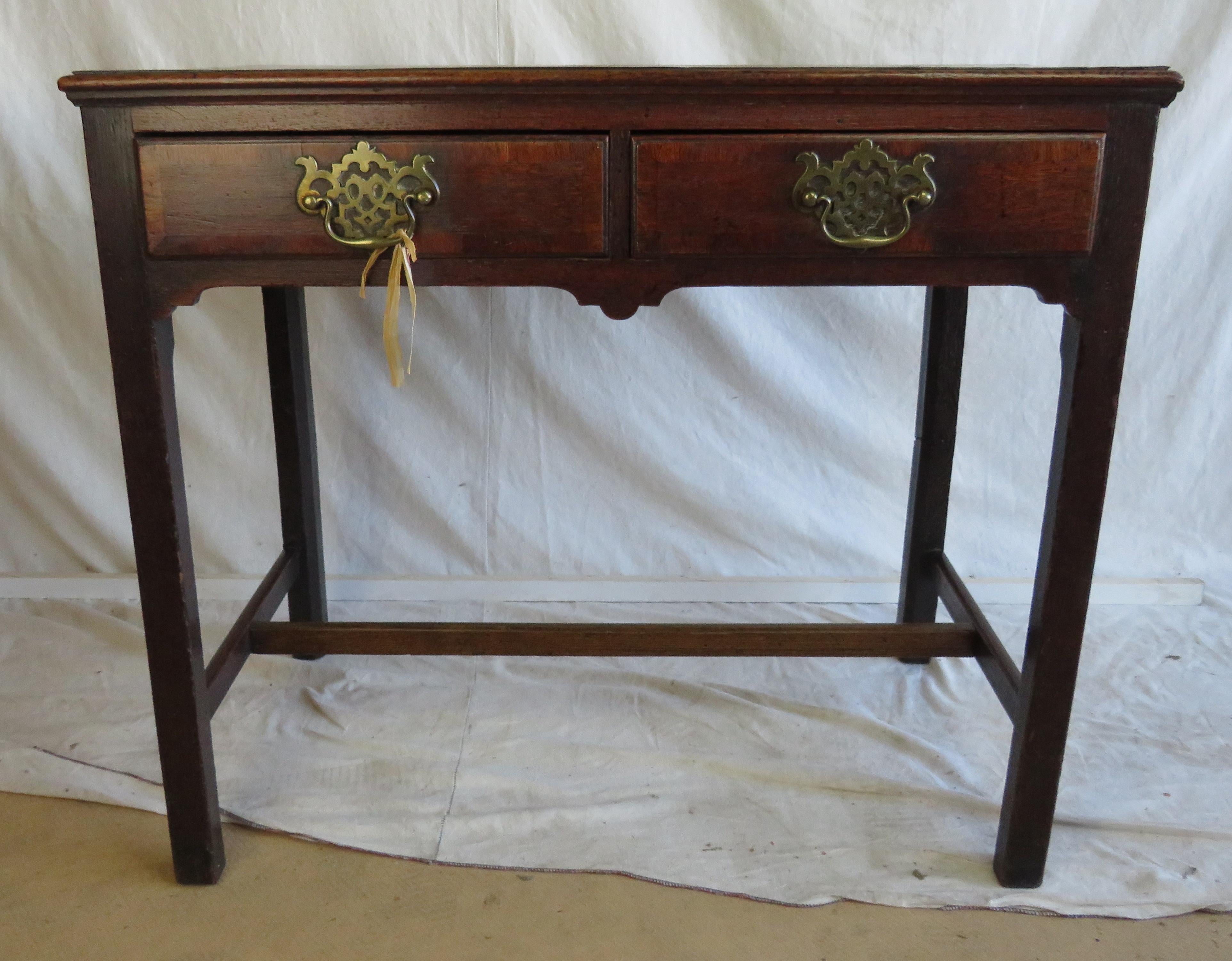 Late 18th century English oak two drawer side table with two side-by-side drawers, each with single brass Chippendale drawer pull, H-stretcher base.