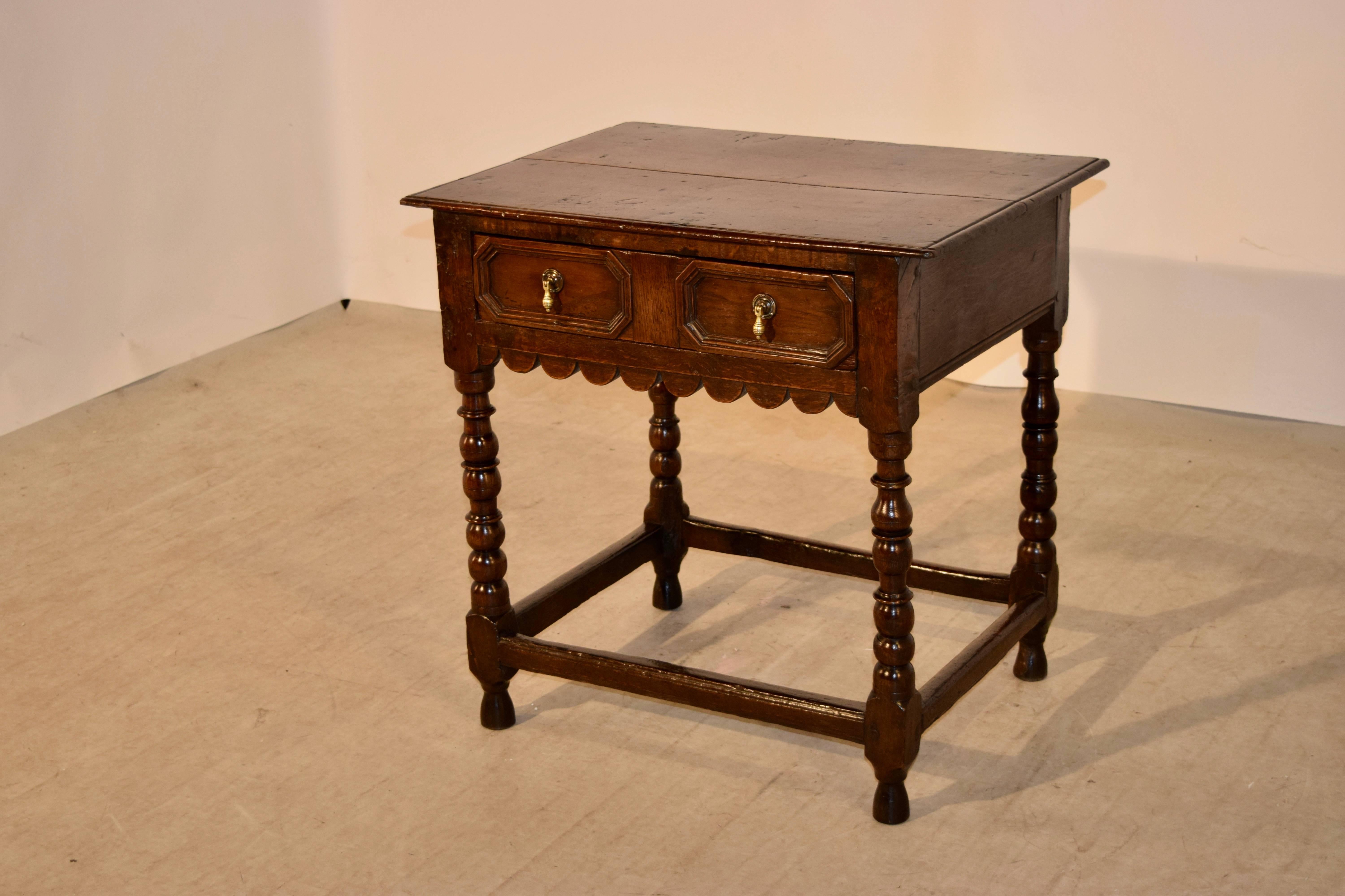 18th century English oak side table with a two plank top, which has beveled edges, following down to a simple apron which contains a single drawer in the front with raised panel geometric molded decoration. There is scalloped decoration underneath
