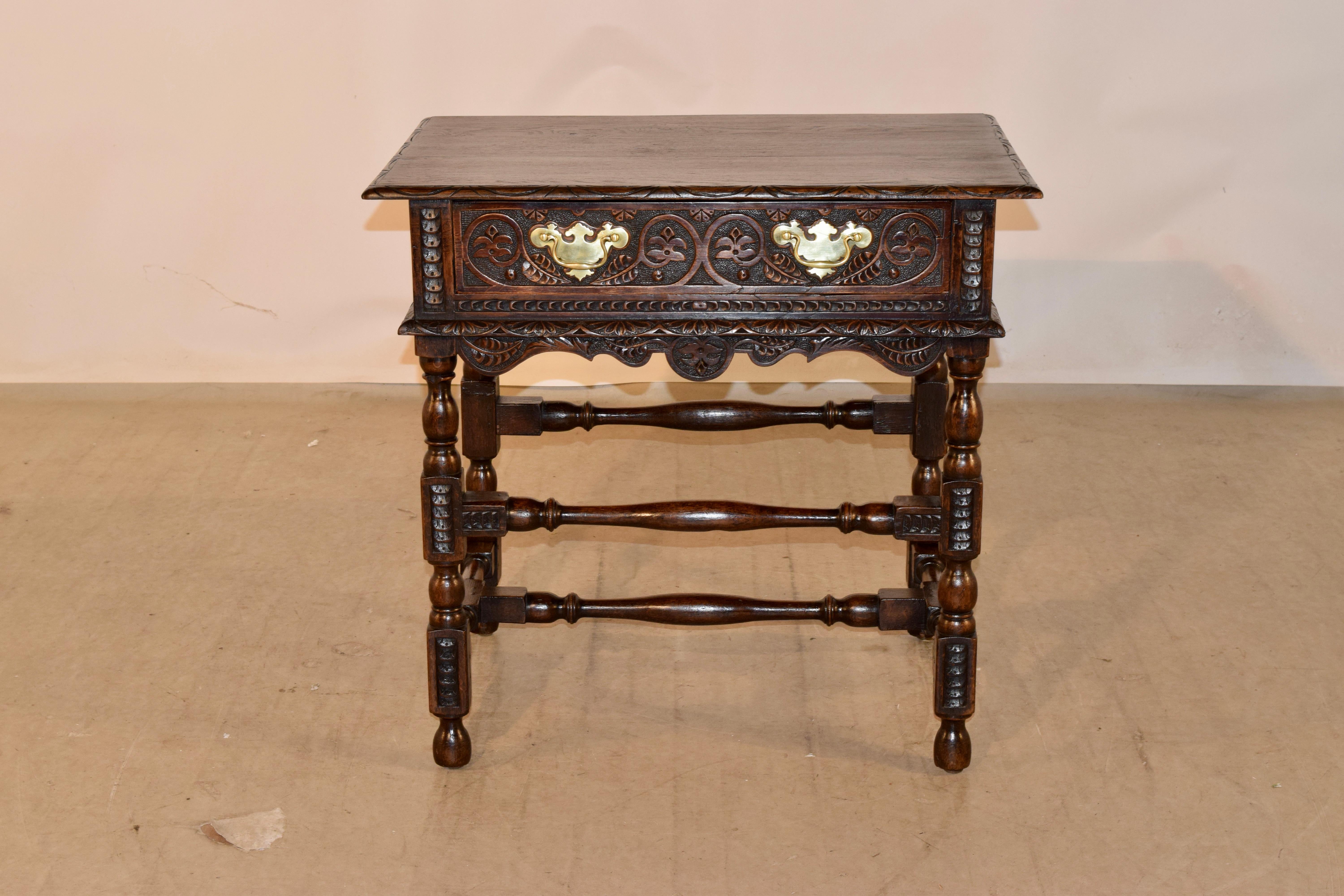 18th century oak side table from England with a two board top, surrounded by a beveled and hand carved decorated edge. The top follows down to a gorgeous hand carved decorated apron, the front containing a single drawer, with a lovely hand carved