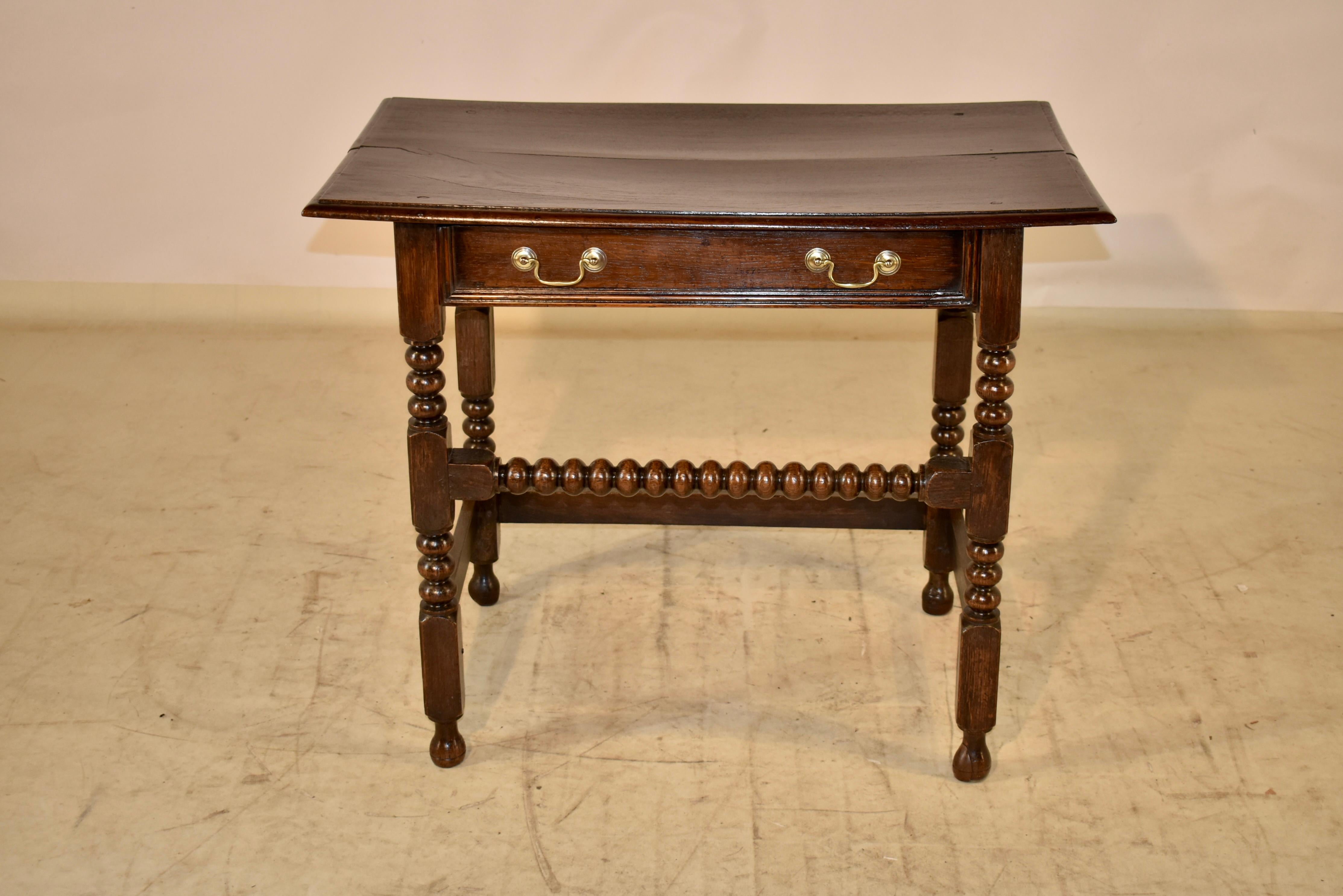 18th century Oak side table from England with a two plank top, which has a beveled edge, following down to simple sides and a single drawer in the front. The drawer has a molded edge. The table is supported on hand turned legs with bobbin and block