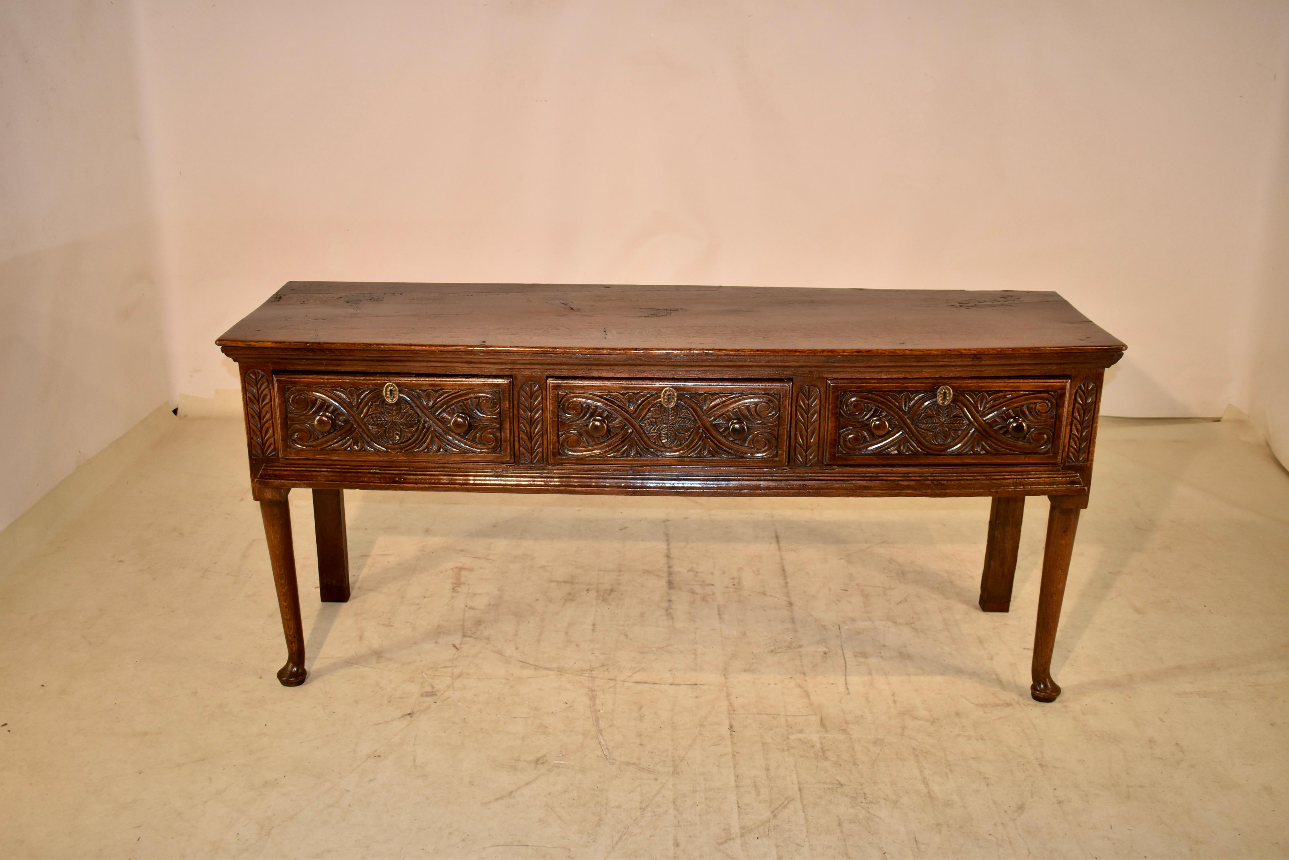 18th century oak sideboard from England. The top is made from one solid plank, and has been added to in the back corner, either for repair or possibly original. The top follows down to simple sides and three drawers in the front, all with hand