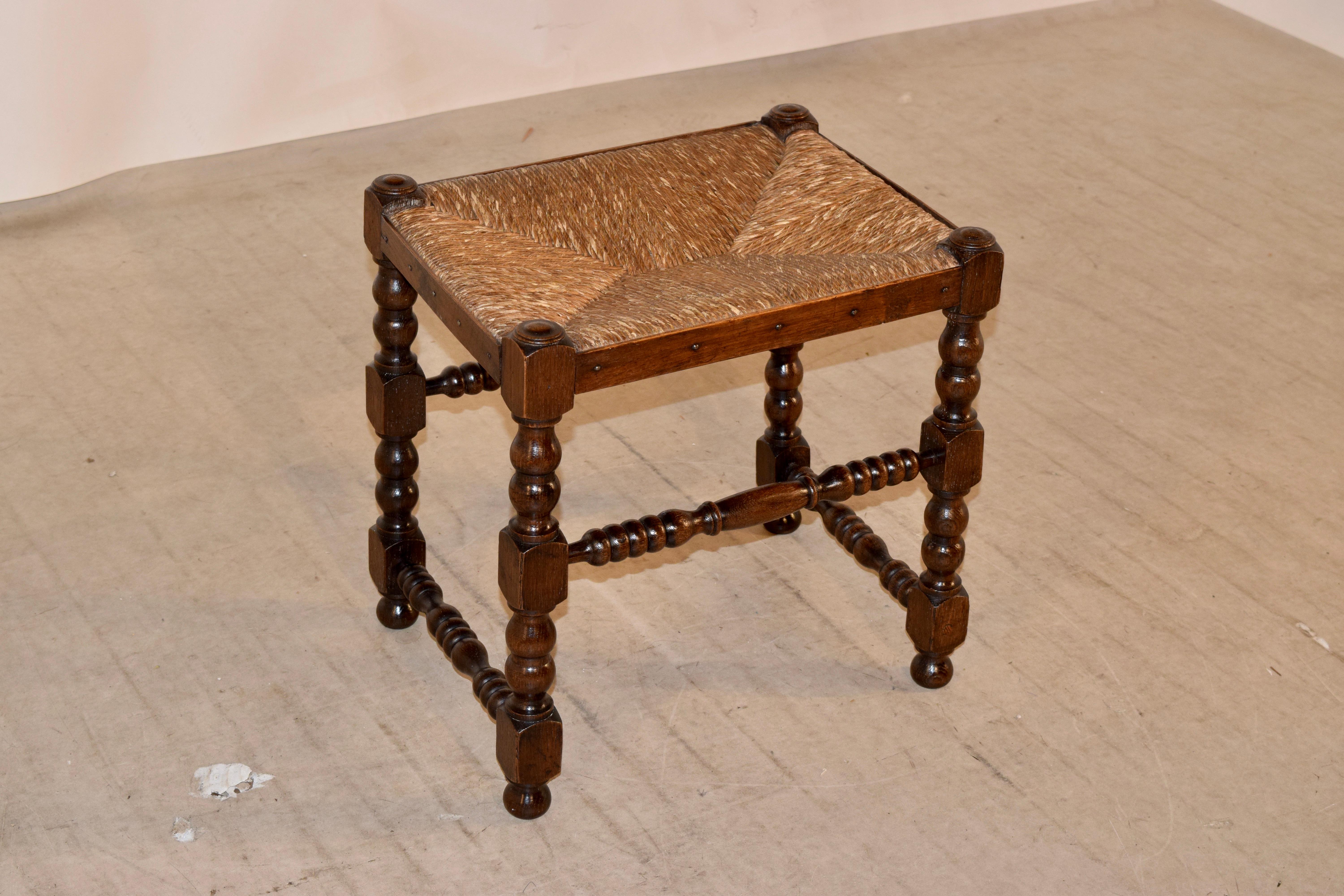 18th century oak stool from England with wonderfully hand-turned legs and matching stretchers with what appears to be its original rush seat.
