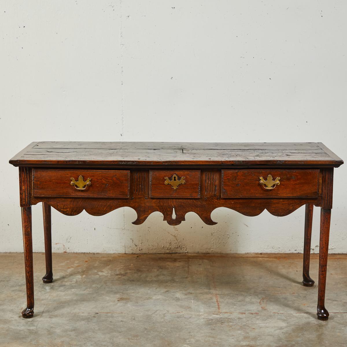 18th century English oak three-drawer dresser base or sofa table server with three frieze drawers and a carved apron raised on slender legs with pad feet. Great as a side table, occasional table, small credenza, or sideboard.