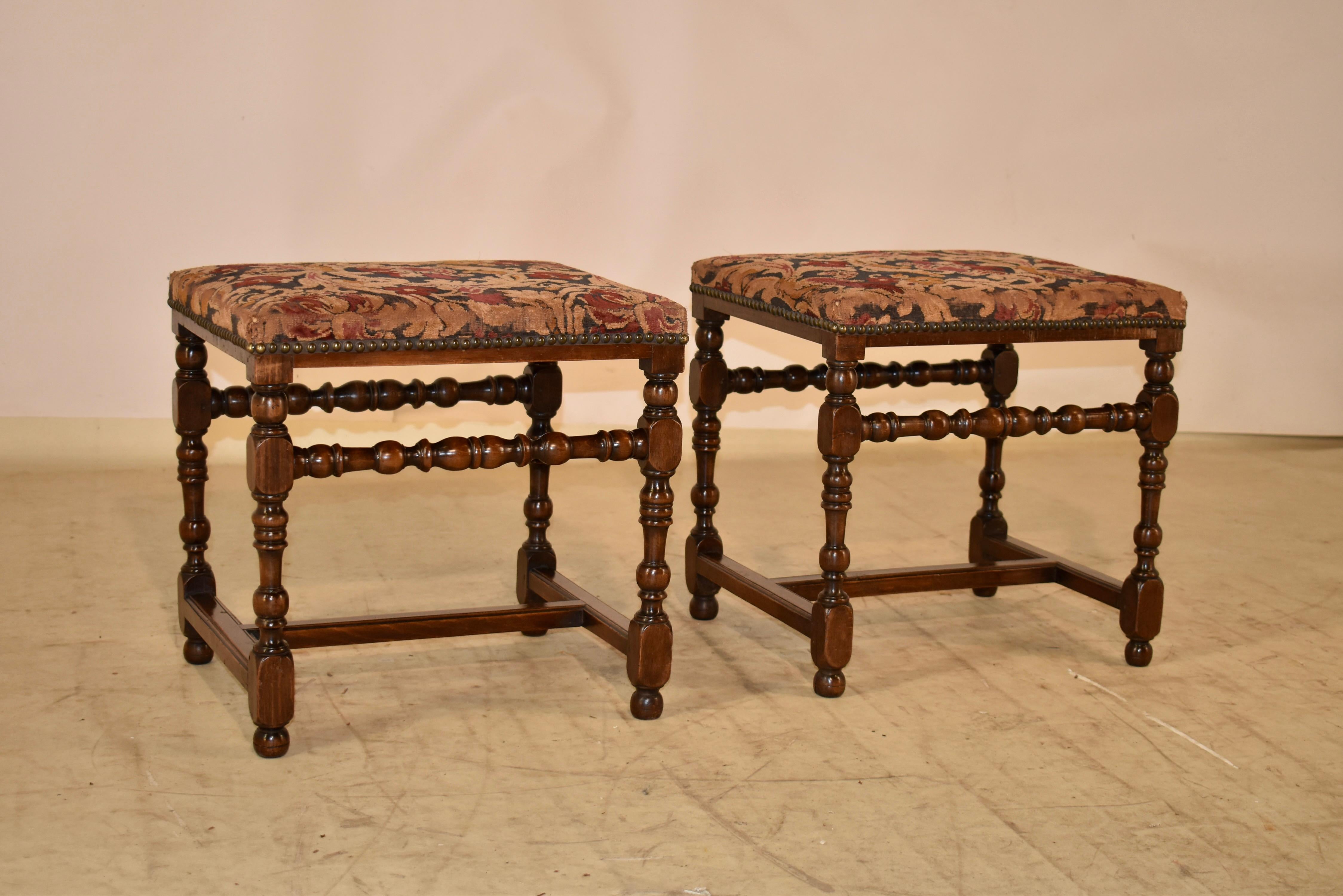 18th century pair of walnut stools from England.  The seats are covered in what appear to be original needlepoints, decorated with nail head trim.  The frames of the stools are made from hand turned walnut and have simple and elegant lines.  The