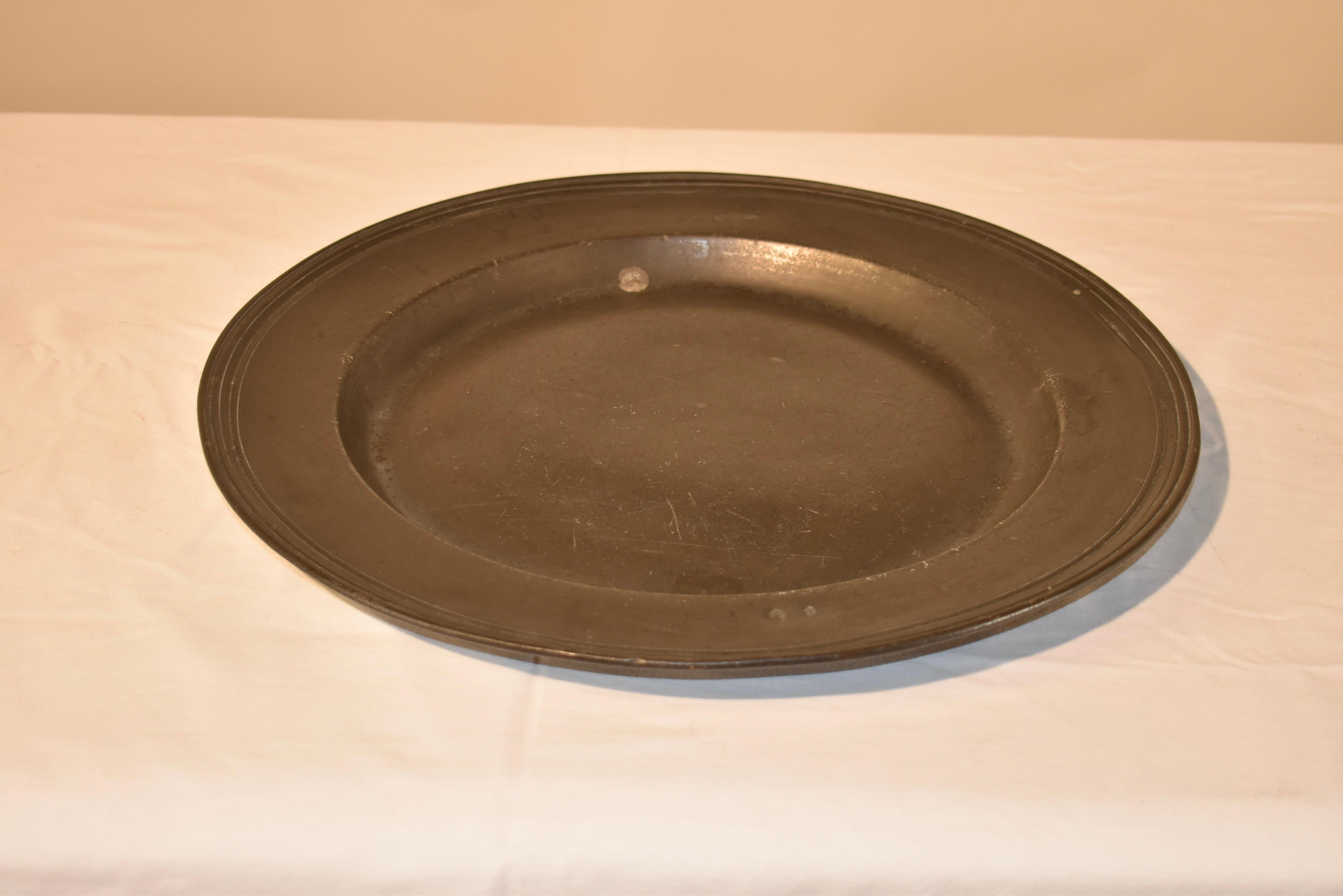 18th century large pewter charger with wide rim and molded edge, which is very elegant, especially for pewter, which was used more frequently for casual dining.  there are two hallmarks on the rim, both of which are photographed.  Plate stand not