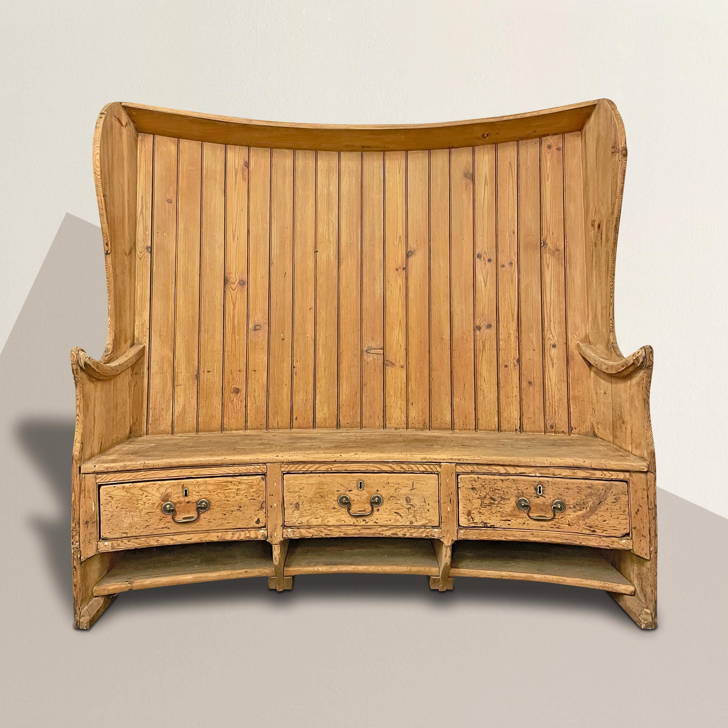 An incredible and playful 18th century English pine settle with a gently curved form, with wing sides, curved arms, and three drawers with brass pulls below the seats. What a fantastic piece indoor dining room, breakfast nook, your living room, or