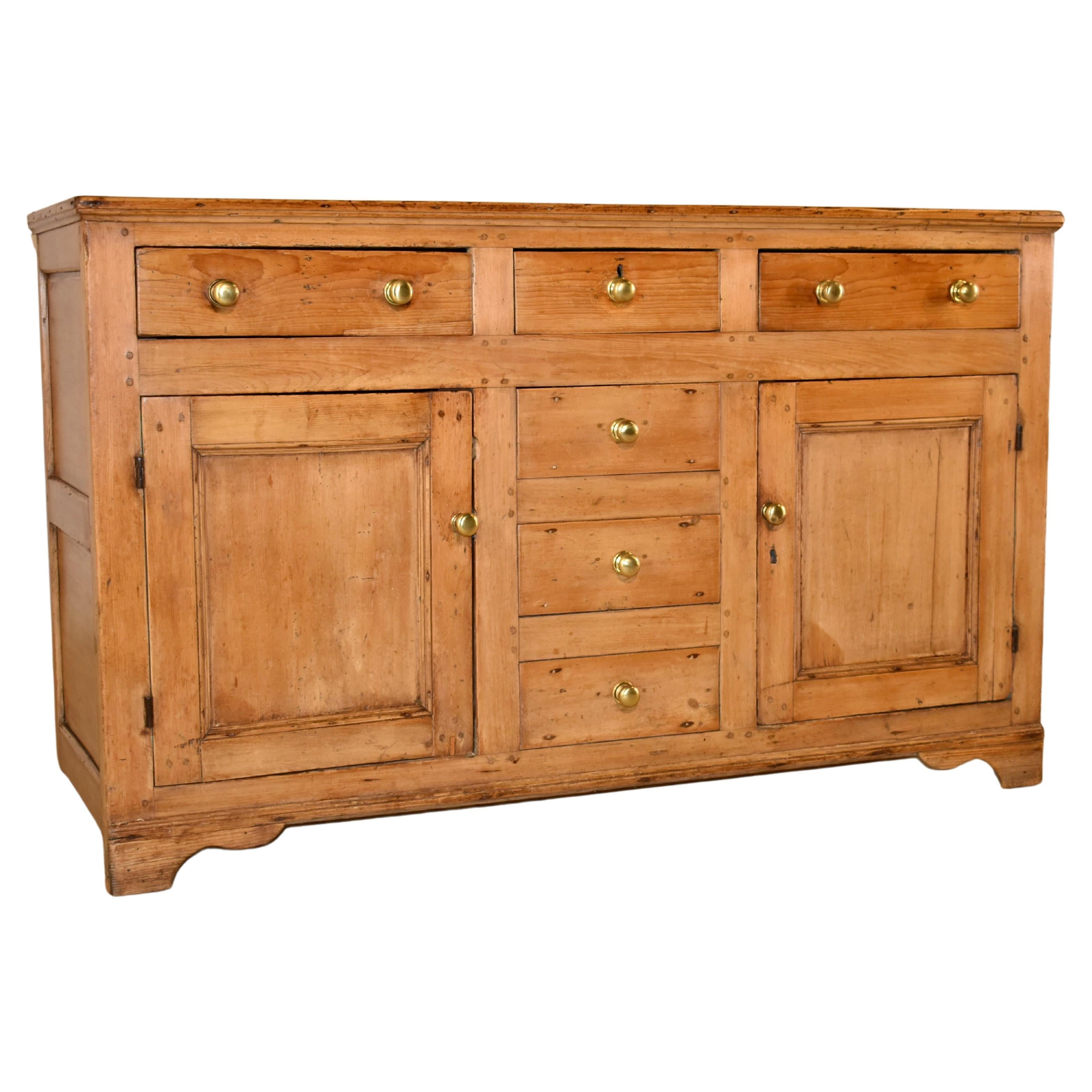 Late 18th century Georgian pine dresser base from England.  the top is made from two planks, and follows down to hand paneled sides.  the front of the piece has three top drawers over a central bank of three false drawers, flanked by single paneled