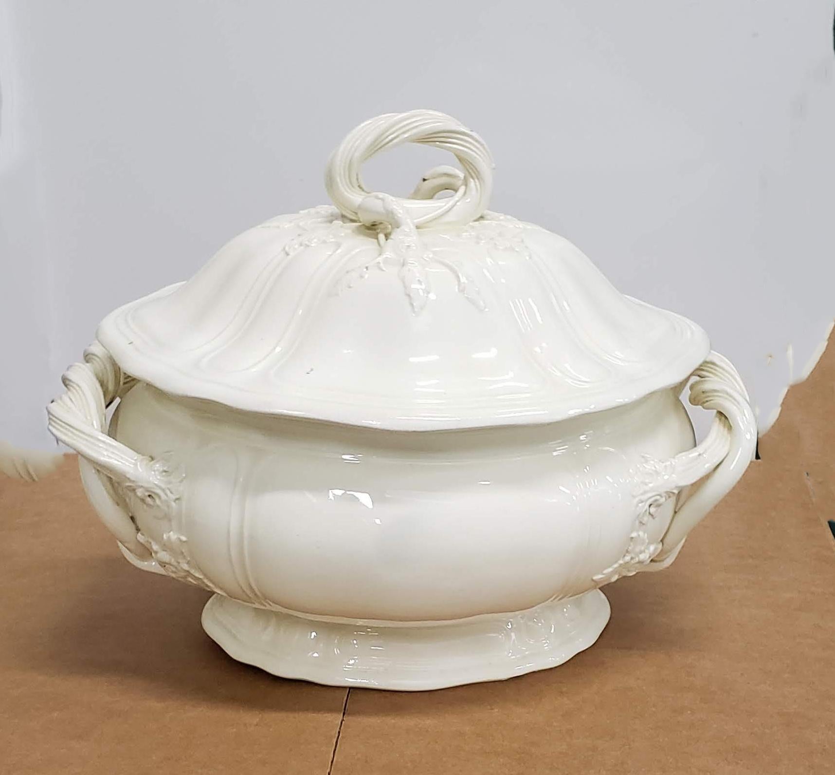 Early English pottery creamware tureen, 
Staffordshire or Yorkshire,
circa 1765
 
The lovely oval lobed tureen with a dark bright cream color has a domed cover with a thick cord-twist raised loop handle with flowering stem, large flower and leaf
