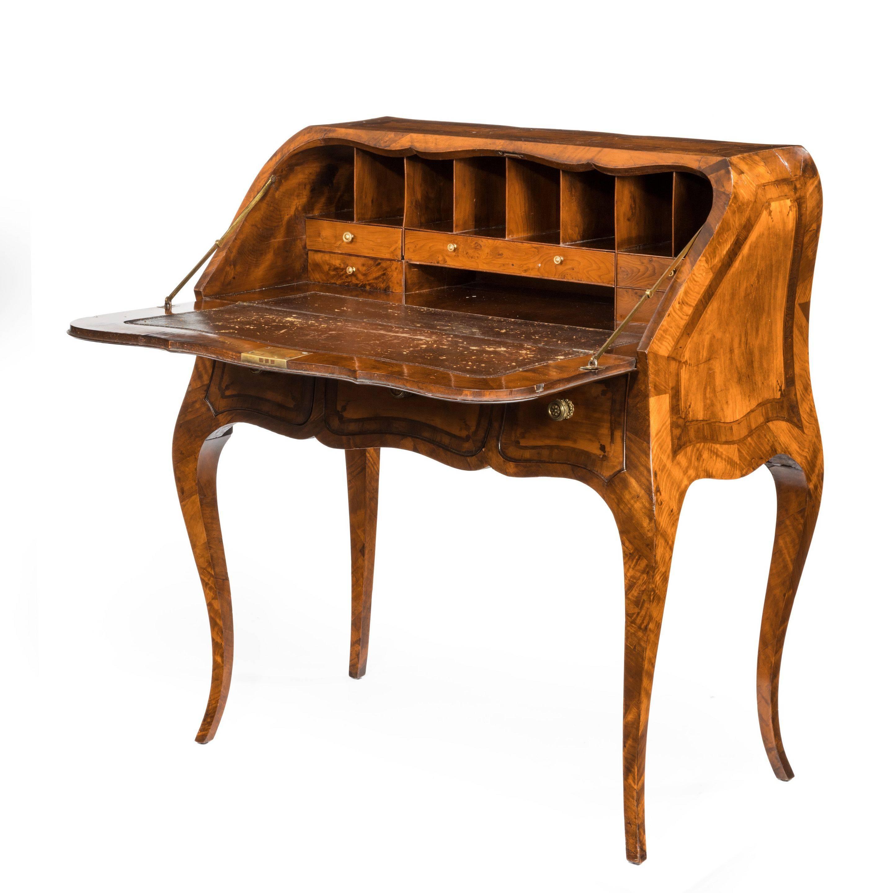 An attractive 18th century English satinwood bureau in French taste, the
shaped top with bombé sides and a fall front opening to reveal pigeon holes,
one long and four short drawers and the original leather, all above three
frieze drawers, set on