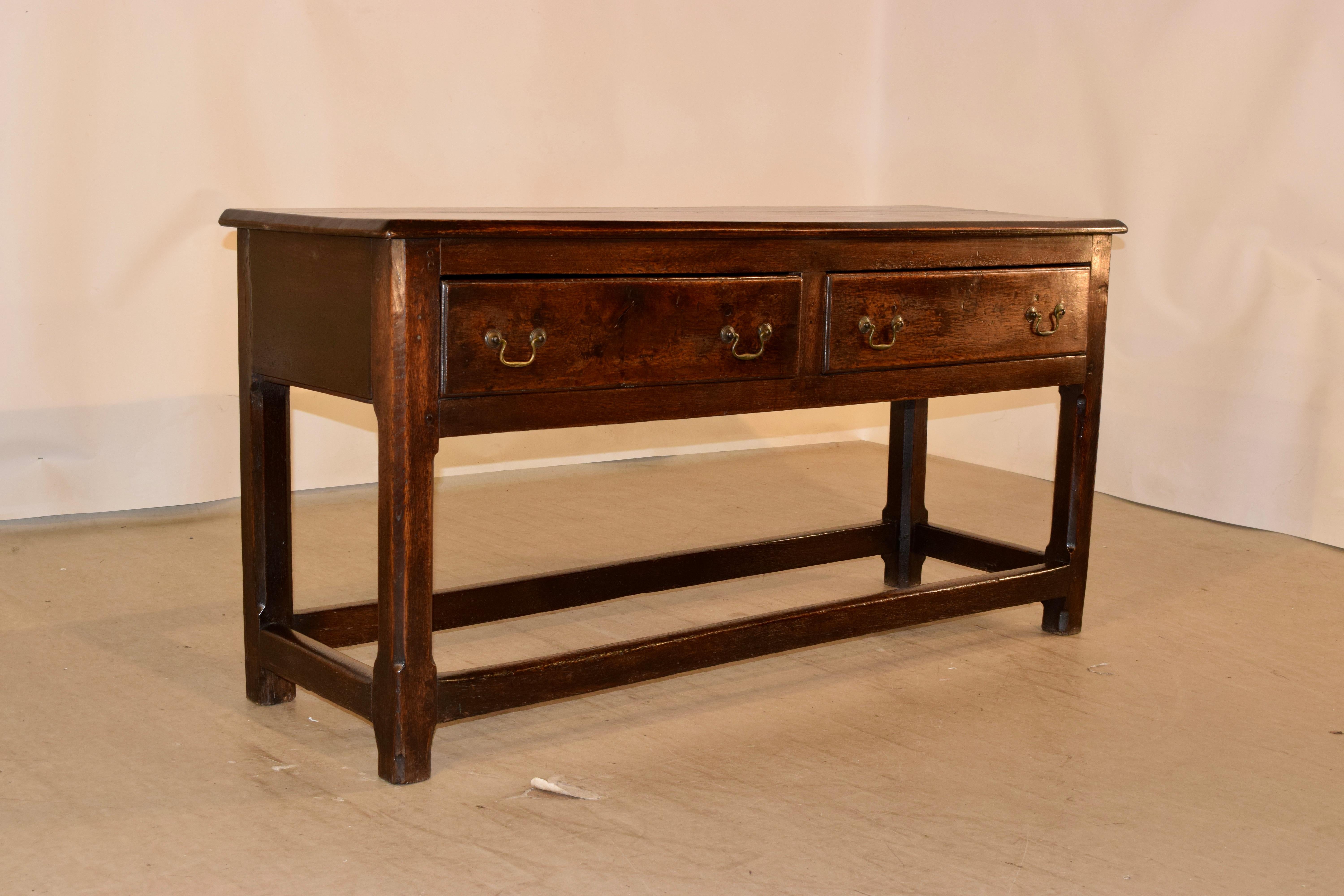 18th century English oak sideboard with simple lines. The top is wonderfully grained and has a beveled edge, following down to simple sides and two drawers in the front. The legs are chamfered in the front and are joined by simple stretchers.