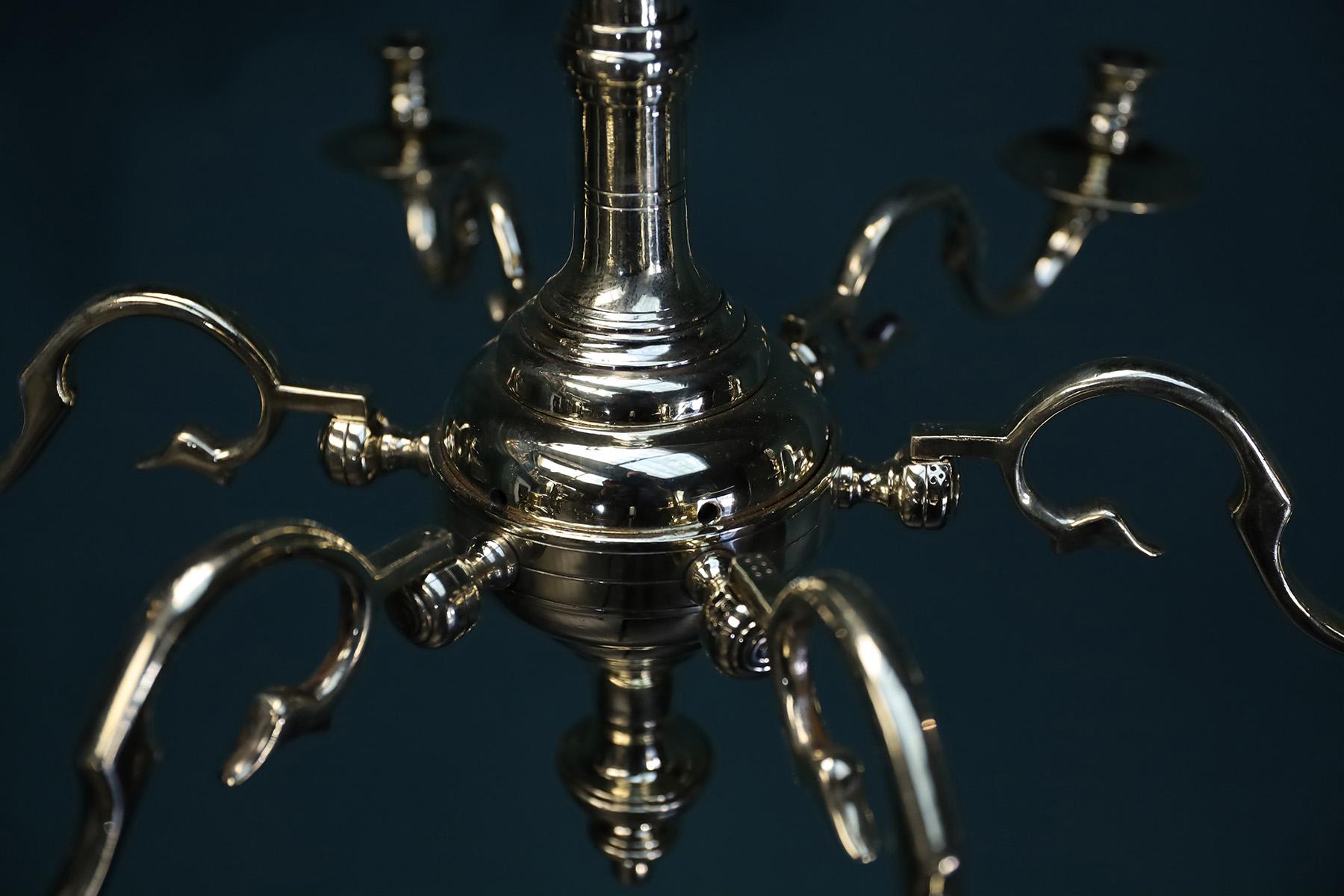 Un elegante lampadario inglese a sei bracci in ottone. Il dettaglio dell'anello a collare sulla sfera centrale sostiene i rami; ogni braccio a s-scroll è marcato individualmente e alloggiato in flange di giunzione mortasate che si estendono
