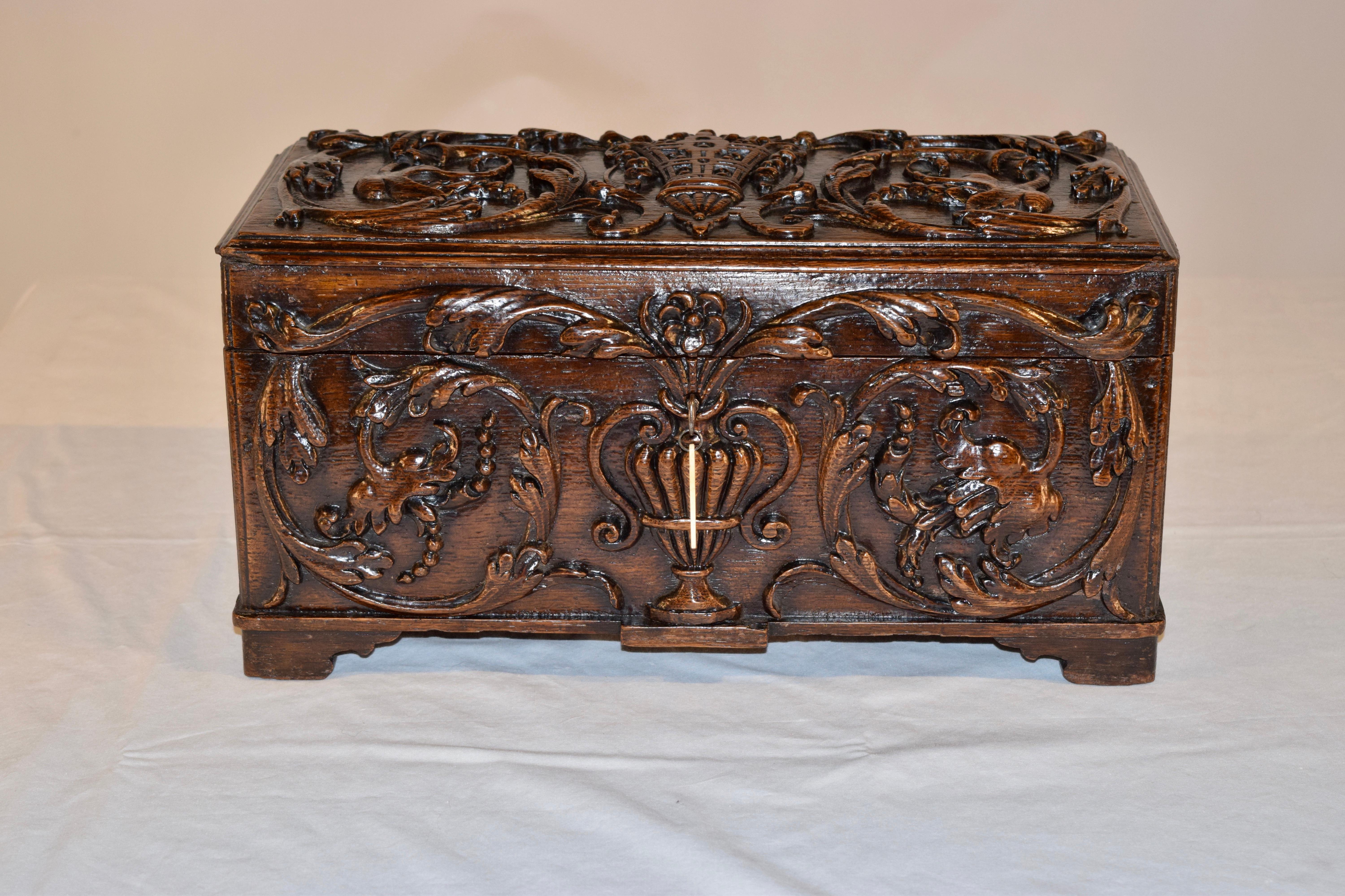 18th century oak tea caddy from England. The top and front of the tea caddy are hand carved decorated with vases, florals and vines. The sides are hand carved decorated with patterns and the back of the box is hand carved decorated with florals and